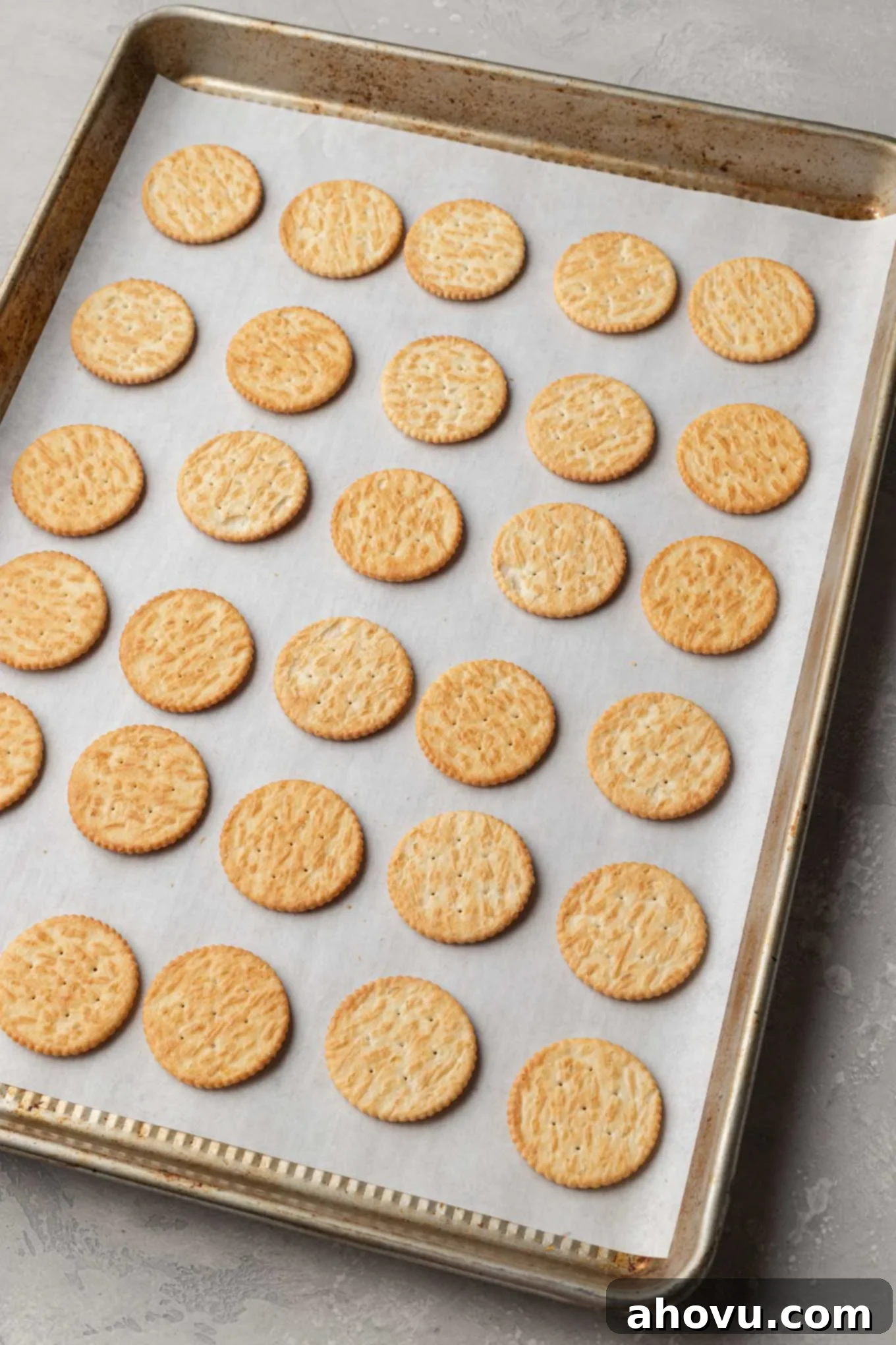 An overhead view of Ritz crackers lined up on a baking sheet. 