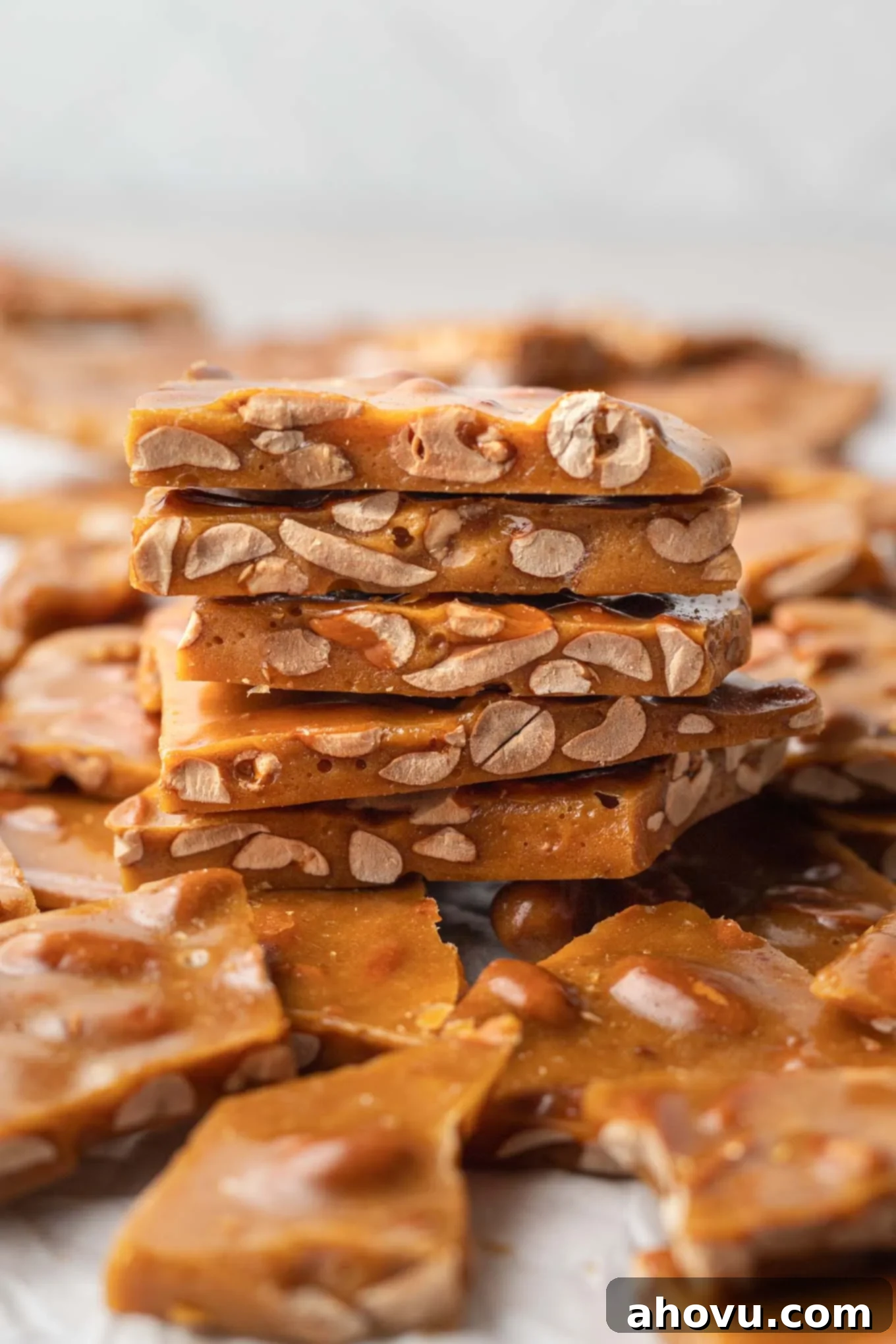 Golden Peanut Brittle 2 A stack of buttery homemade peanut brittle, seen from the side. Golden brown and glistening, loaded with peanuts.