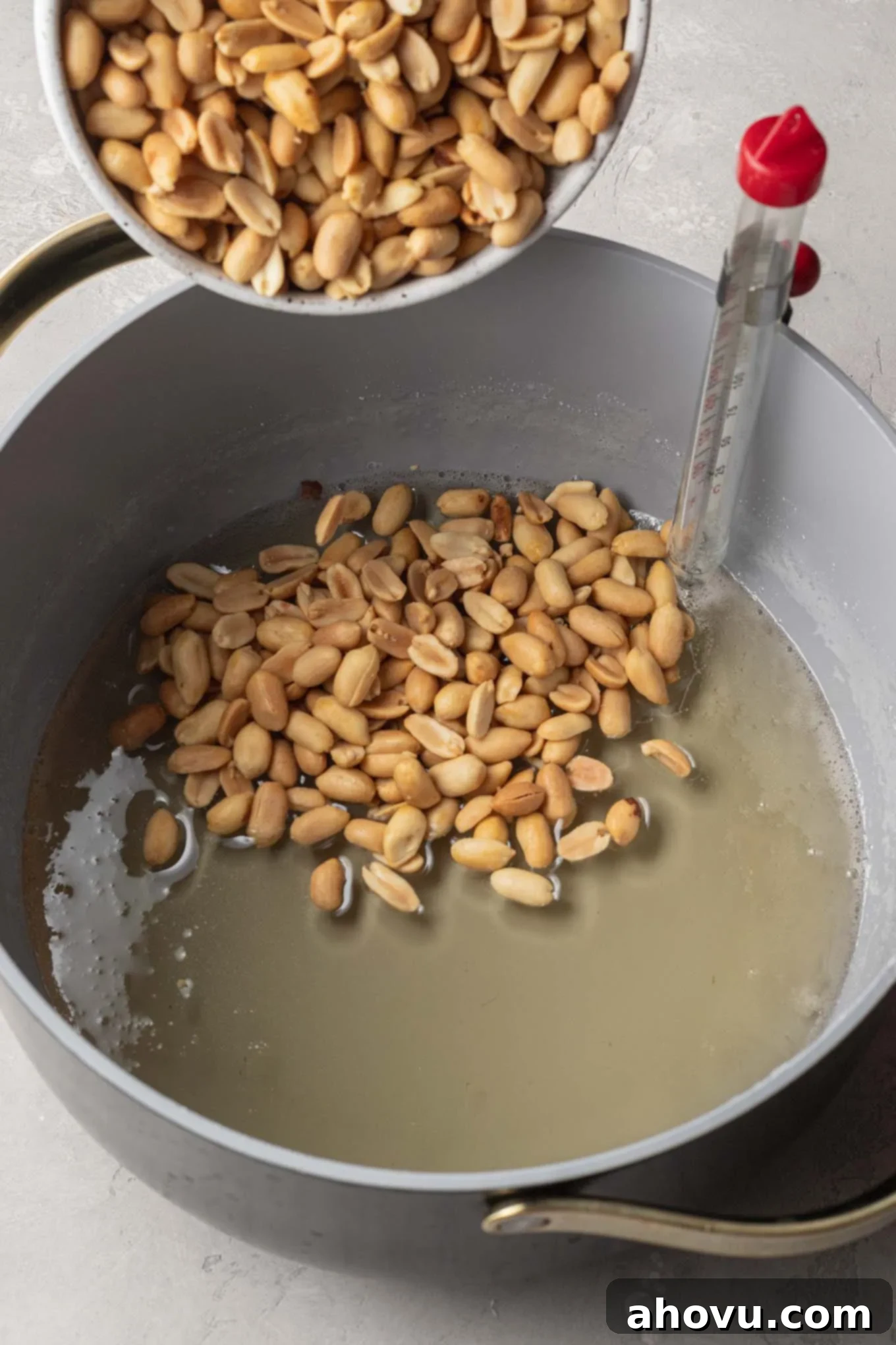 Golden Peanut Brittle 5 An overhead view of peanuts being mixed into a cooked brittle mixture in a saucepan, reaching the hard-crack stage.