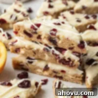 Several iced cranberry bliss bars stacked on top of each other.