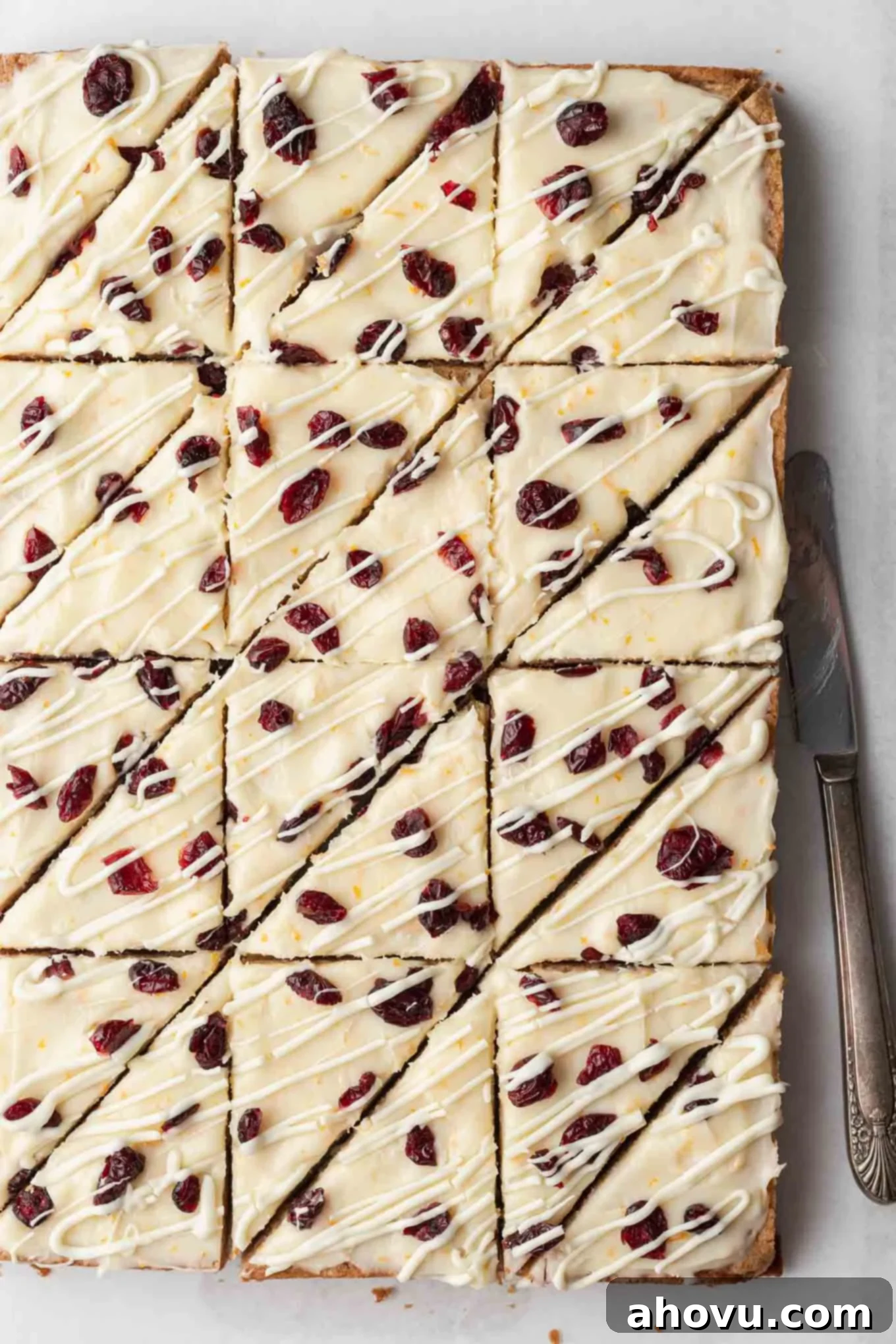 An overhead view of beautifully decorated copycat cranberry bliss bars, freshly frosted and drizzled with white chocolate, sliced into perfect triangles, ready for serving.