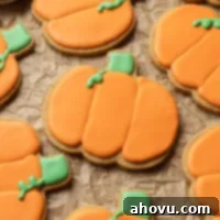 Several iced pumpkin sugar cookies on a piece of parchment paper.