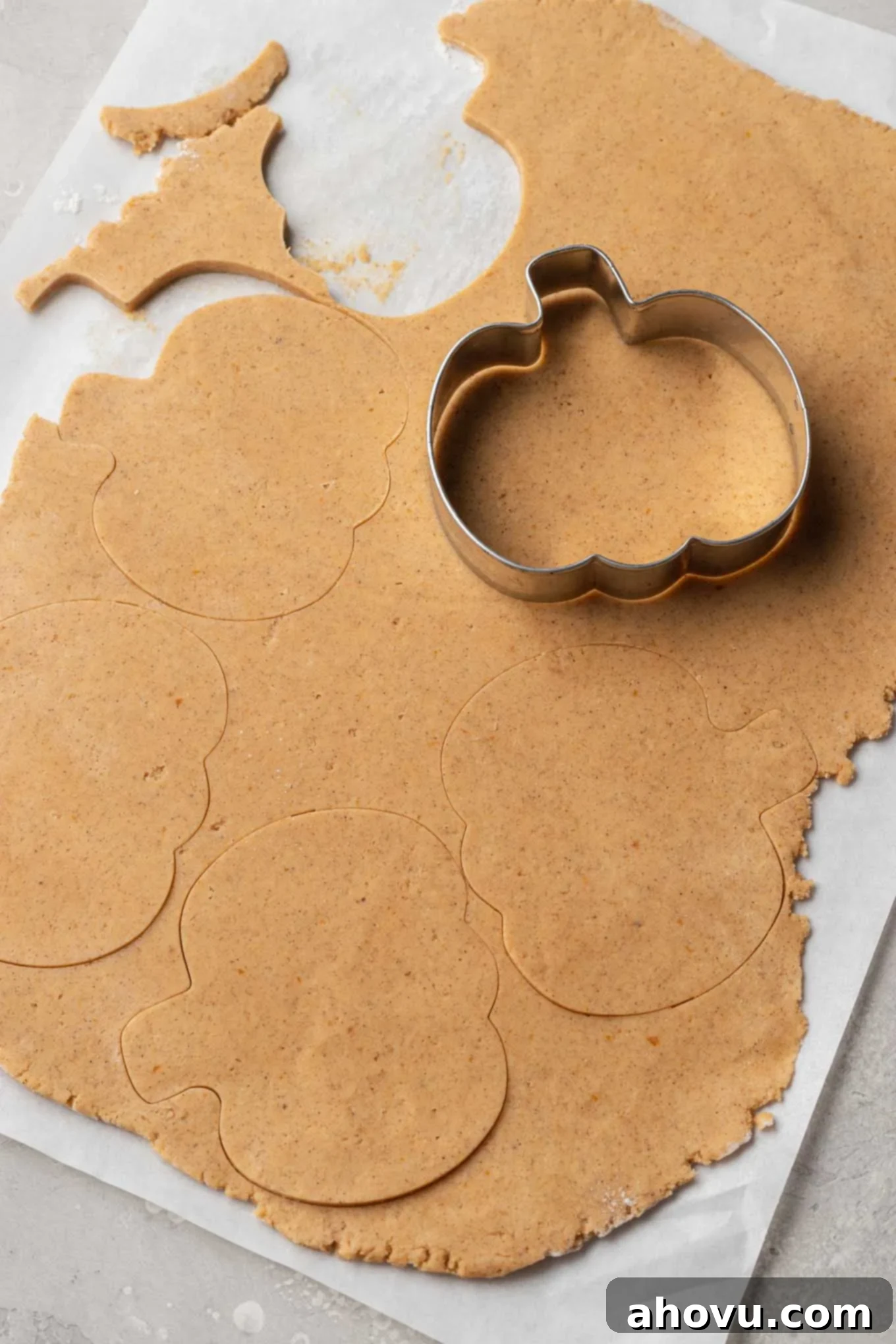 Autumn Pumpkin Sugar Cookies 9 An overhead view of pumpkin cookie dough being cut into pumpkin shapes.