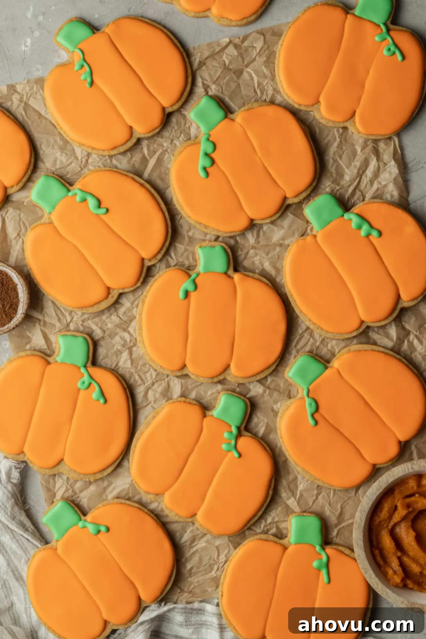 Autumn Pumpkin Sugar Cookies 10 An overhead view of decorated pumpkin cookies on parchment paper.
