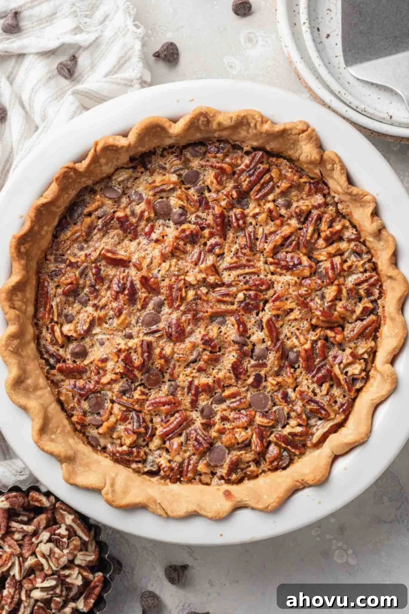 Decadent Chocolate Pecan Dream 2 An overhead view of a beautifully baked chocolate pecan pie in a pristine white ceramic pie plate, ready to be sliced and served.