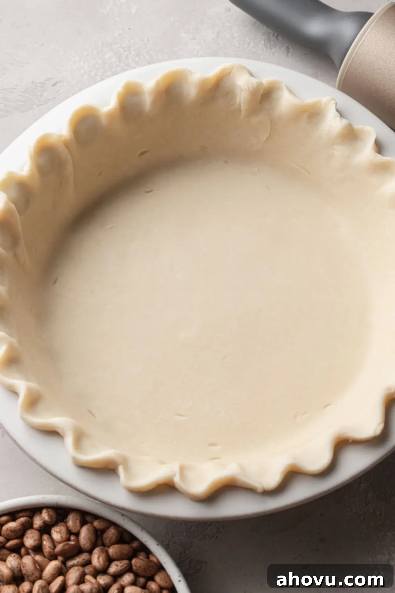 Decadent Chocolate Pecan Dream 5 An overhead view of the rolled pie dough expertly pressed and crimped into a white ceramic pie plate, prepared for baking.