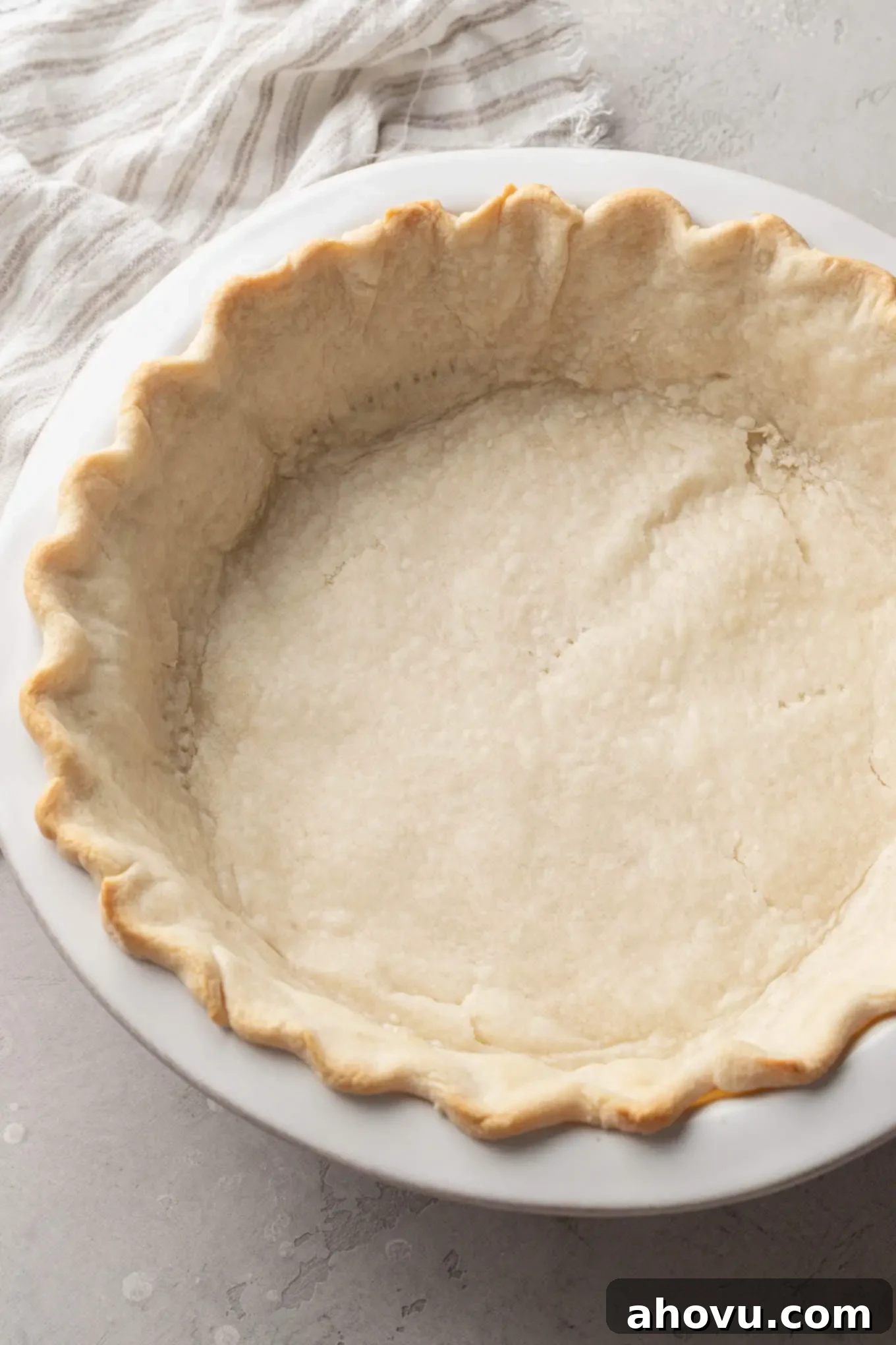 Decadent Chocolate Pecan Dream 7 An overhead view of a perfectly partially baked pie crust, golden at the edges, resting in a white ceramic pie plate after blind baking.