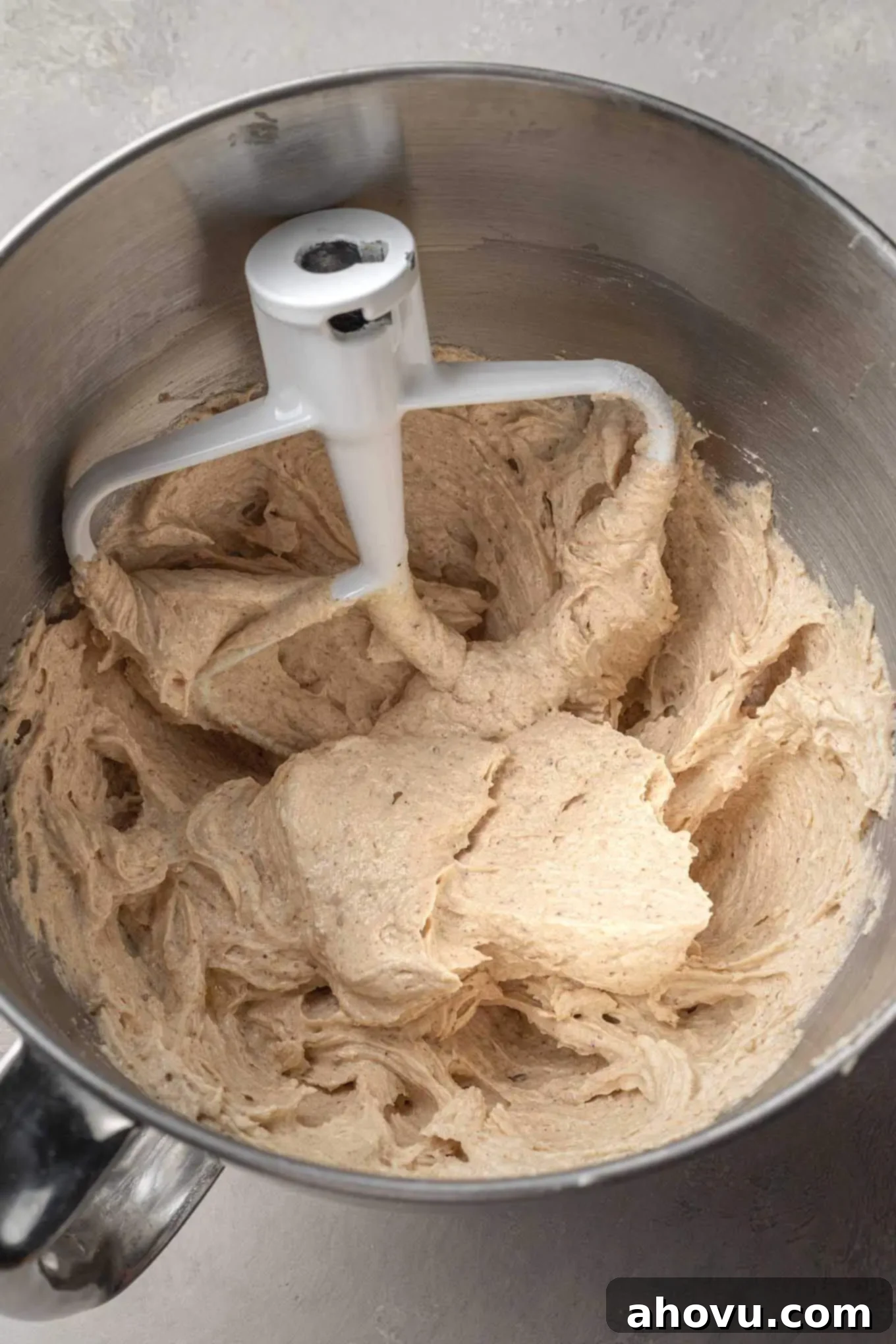 An overhead view of the wet ingredients needed for snickerdoodle cookies in a mixing bowl, with a paddle attachment. 