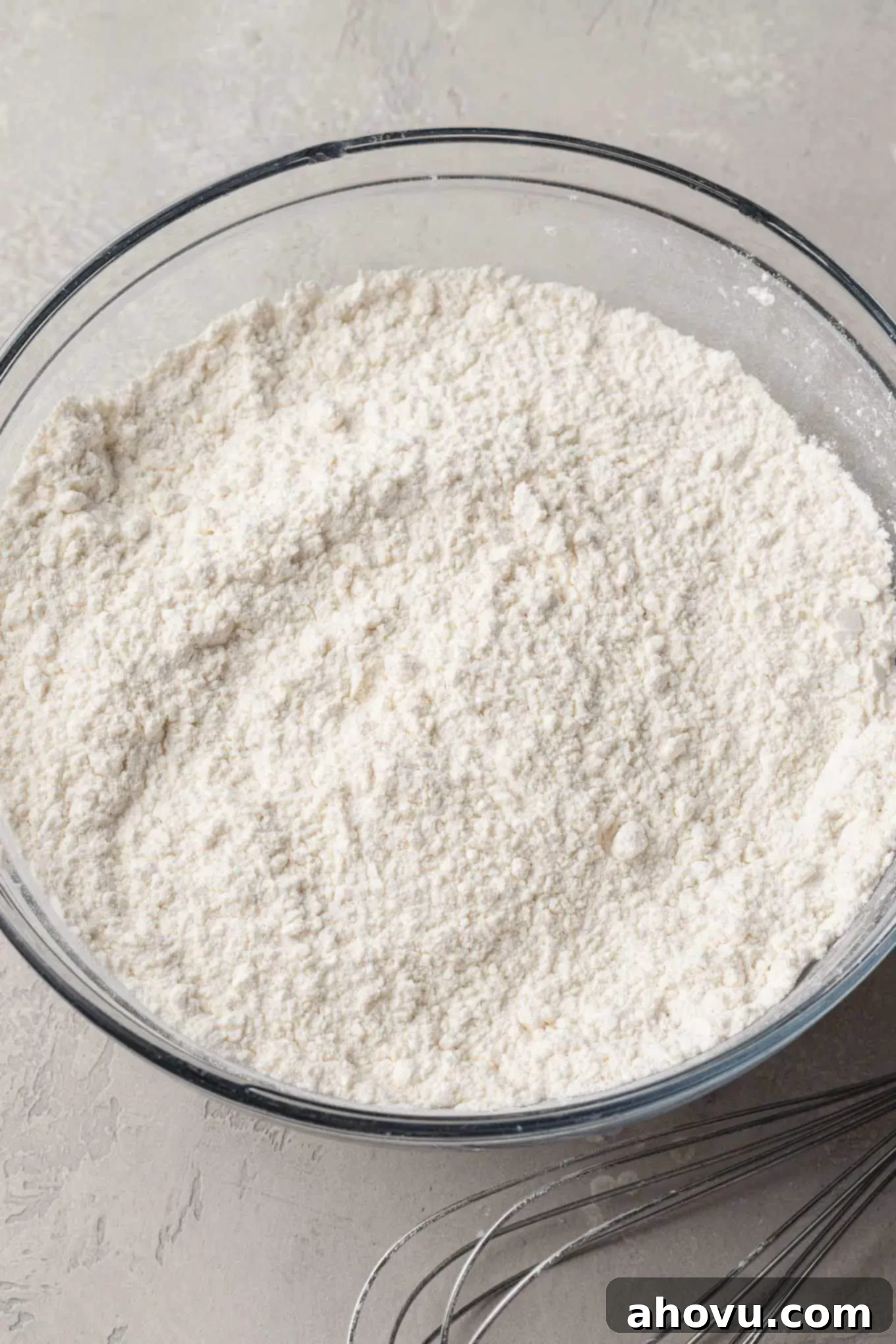 A glass mixing bow with both types of flours, baking soda, and salt whisked together.