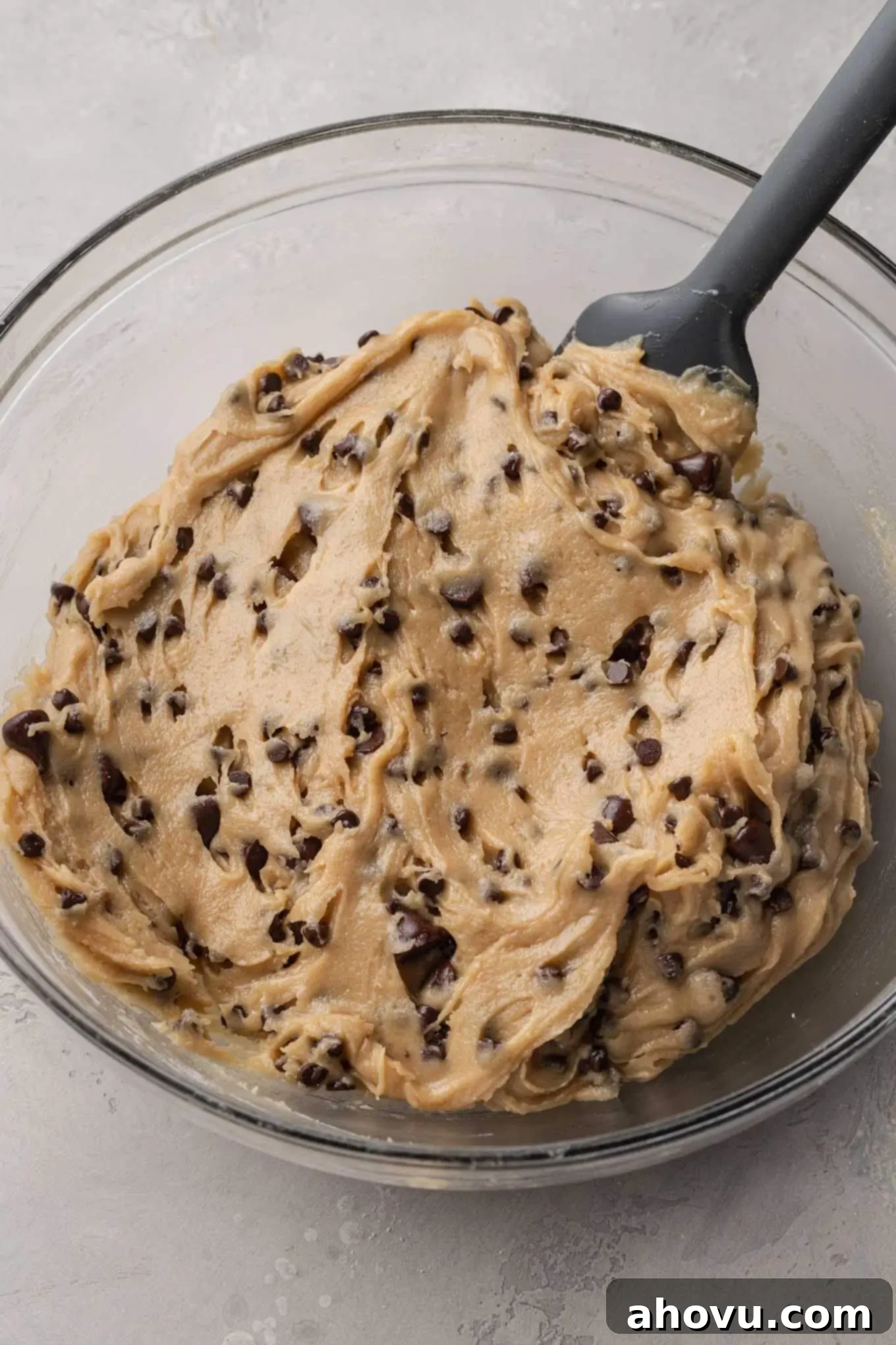 A glass mixing bowl filled with the finished chocolate chip cookie dough.