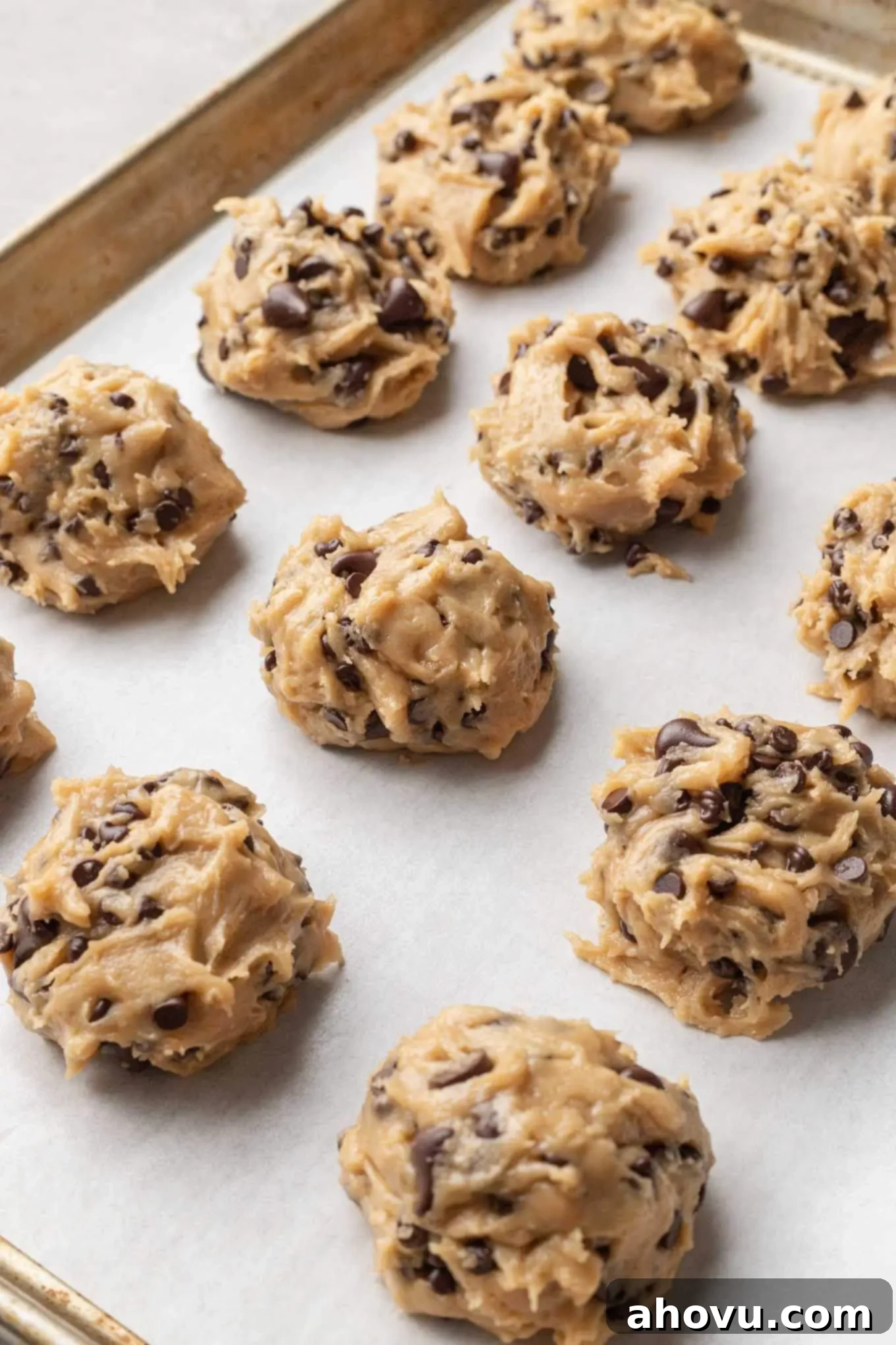 A baking sheet lined with parchment paper with balls of cookie dough scooped on top.