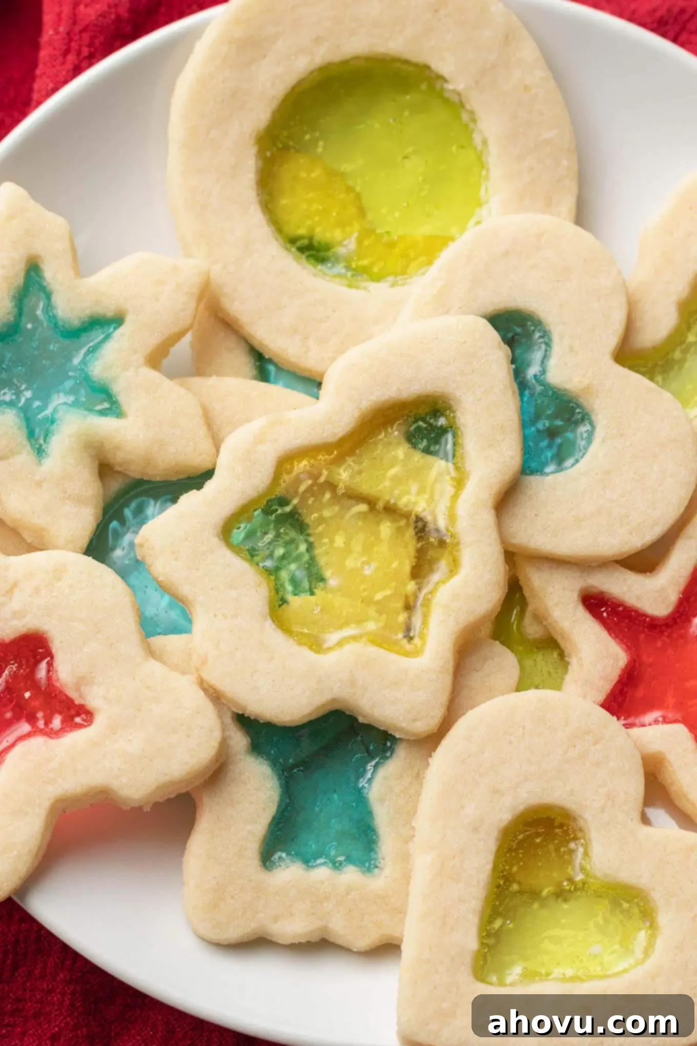 A close-up, overhead view of a plate of stained glass cookies, showcasing their vibrant, translucent centers.