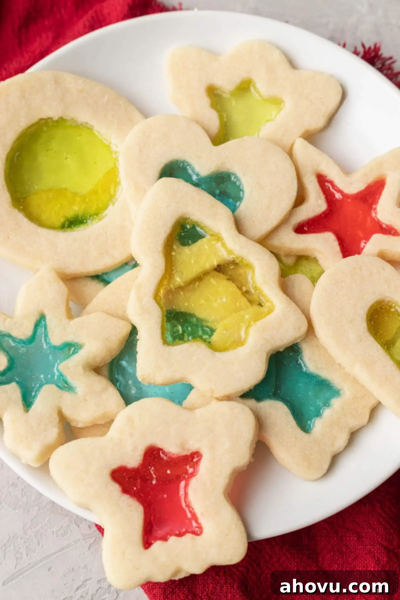A close-up, overhead view of a perfectly arranged plate of stained glass cookies, highlighting their festive colors and intricate cutouts.