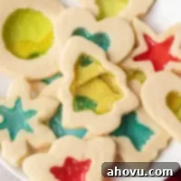 An overhead view of several stained glass cookies on a white plate.