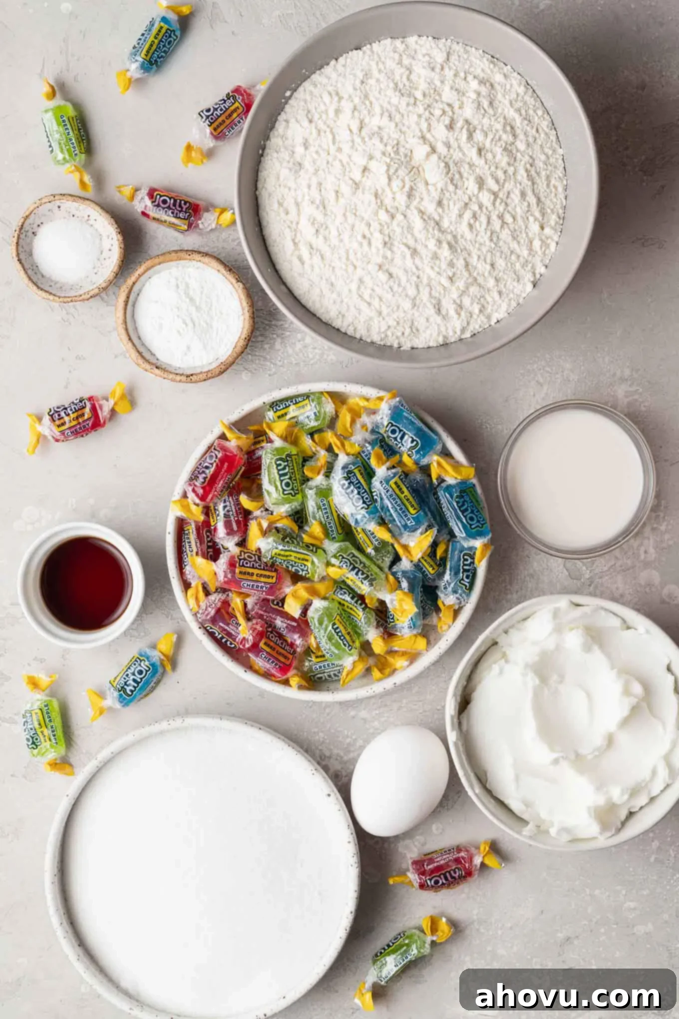 An overhead view of the ingredients needed to make vibrant stained glass window cookies, including flour, sugar, shortening, and colorful Jolly Ranchers.