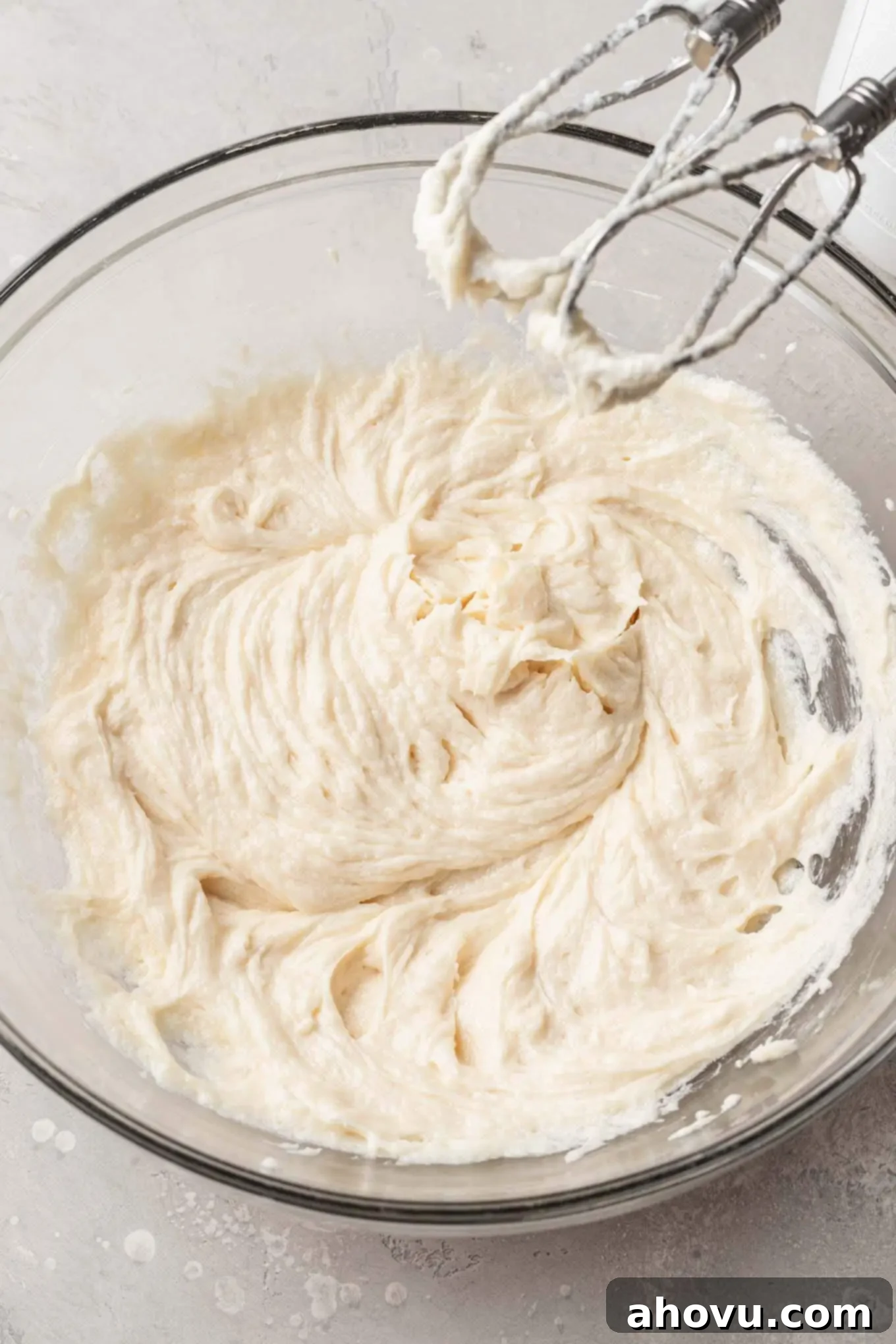 The wet ingredients for sugar cookie dough, including egg, milk, and vanilla, fully mixed together to a smooth consistency in a glass bowl.