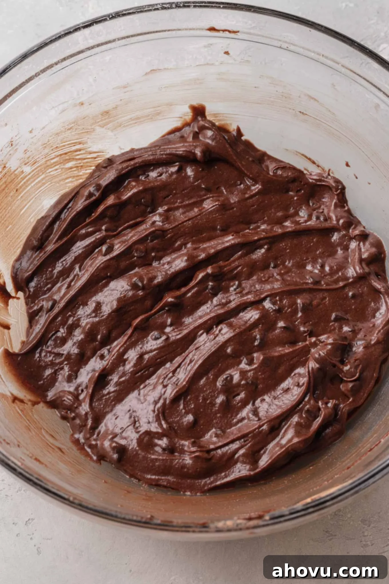 An overhead view of brownie batter in a glass mixing bowl. 