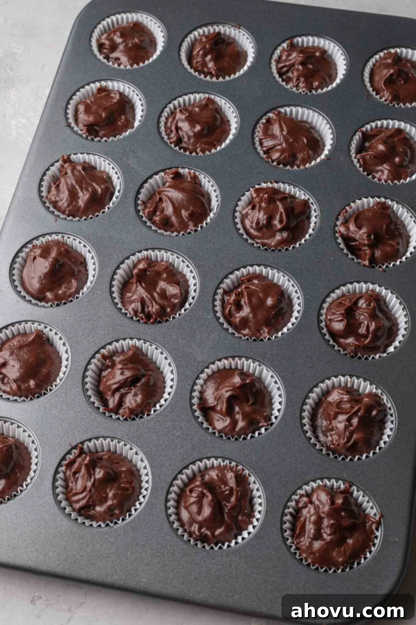 An overhead view of mini brownies in a mini muffin pan, ready to be baked. 