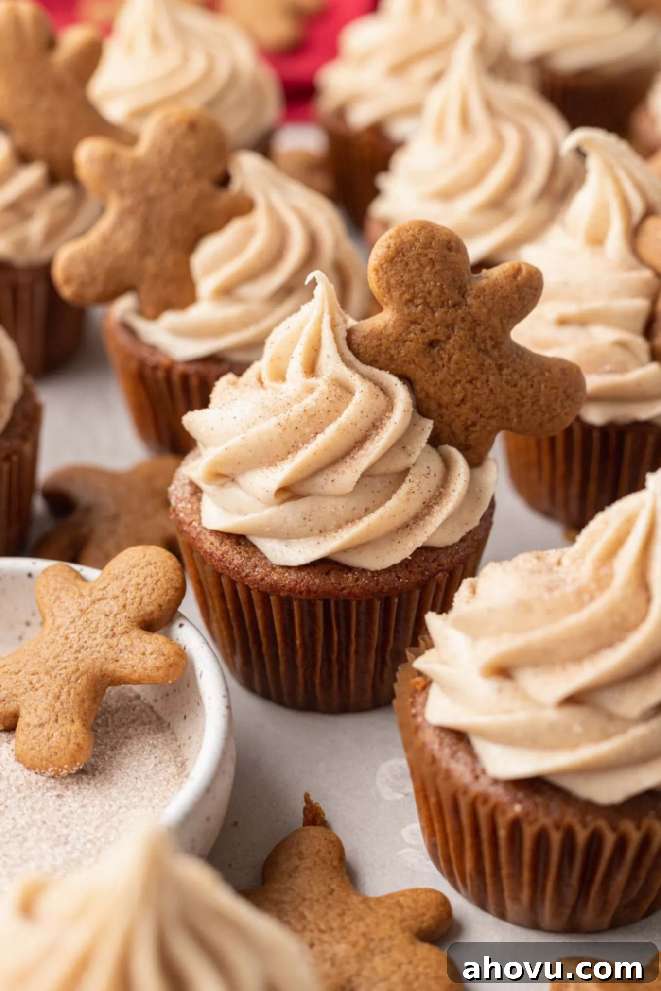 Gingerbread cupcakes piped with cinnamon cream cheese frosting and topped with a mini gingerbread cookie. 