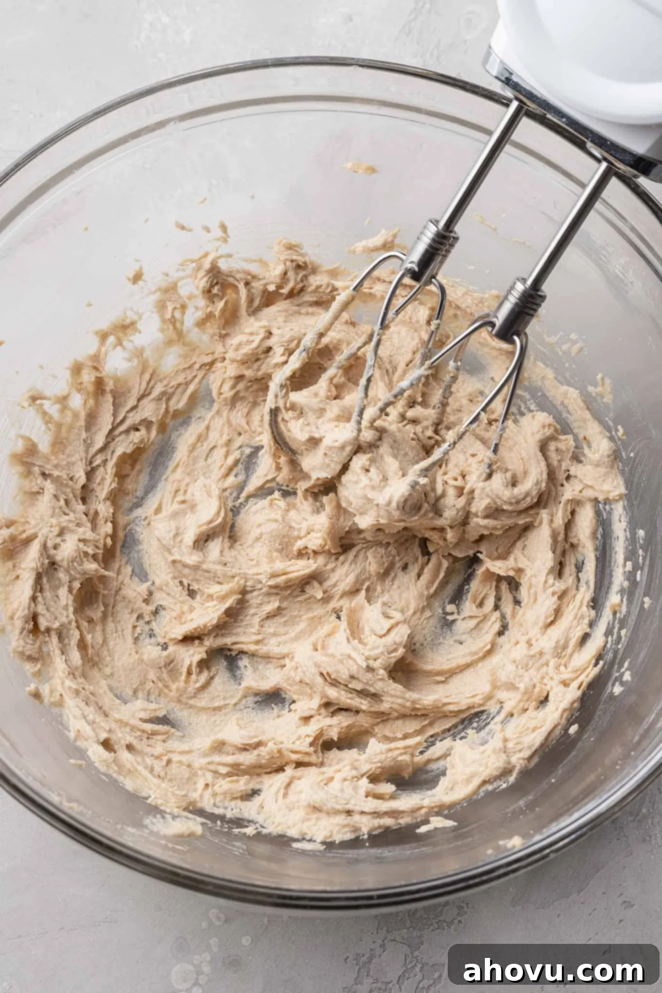 An overhead view of creamed butter and sugar in a glass mixing bowl. 