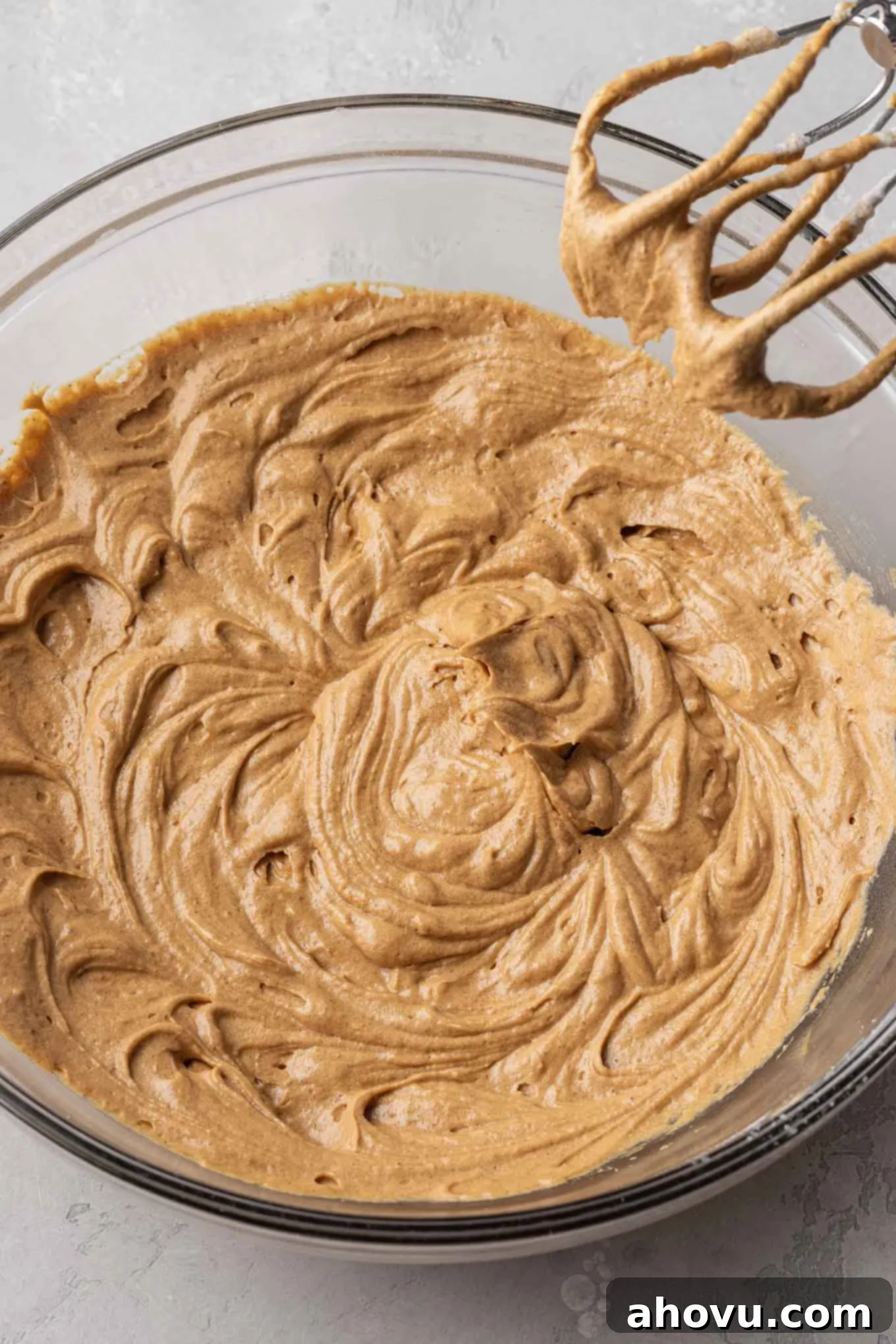 An overhead view of gingerbread cupcake batter in a glass mixing bowl. 