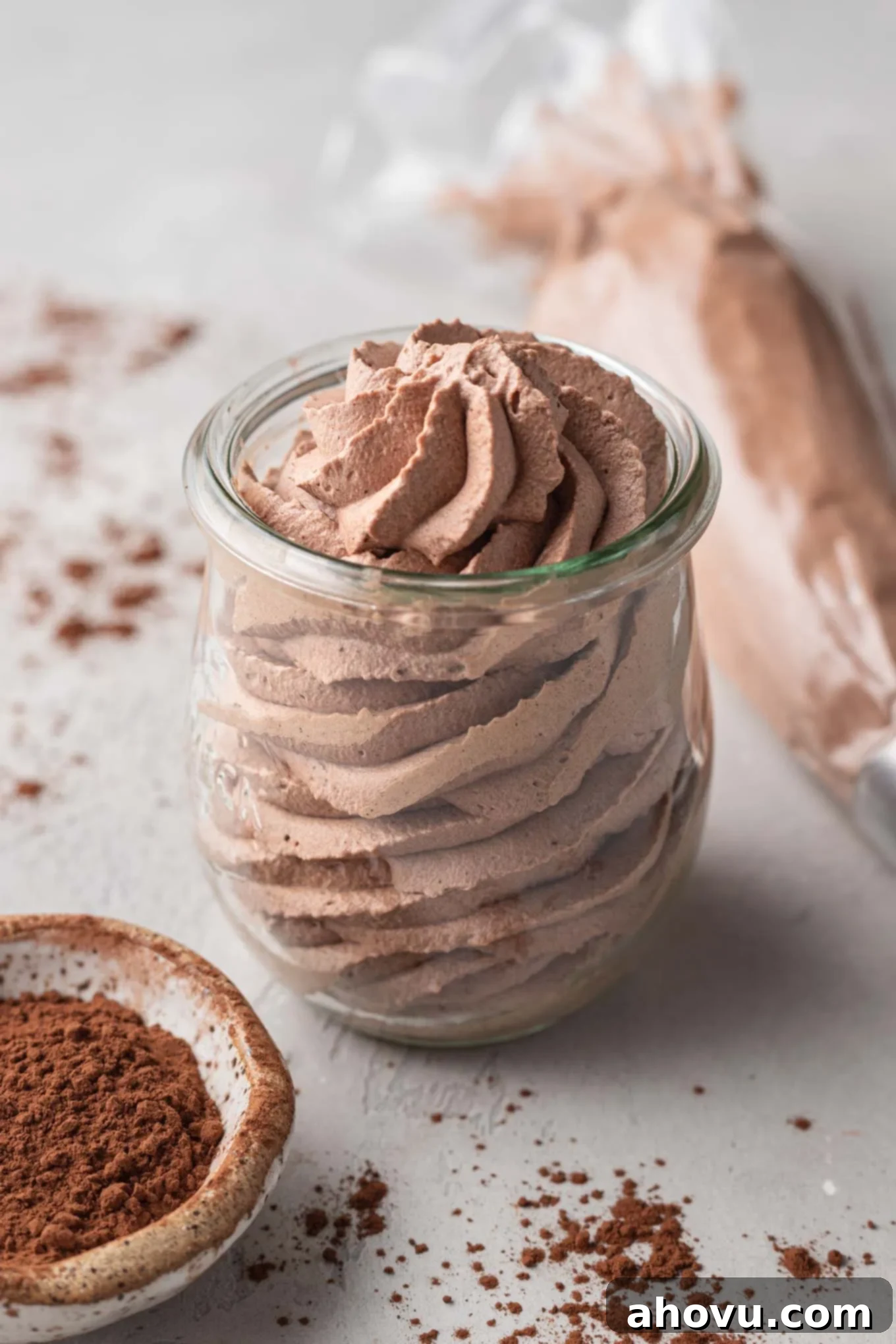 A jar of chocolate whipped cream with a small bowl of Dutch process cocoa powder resting next to it.