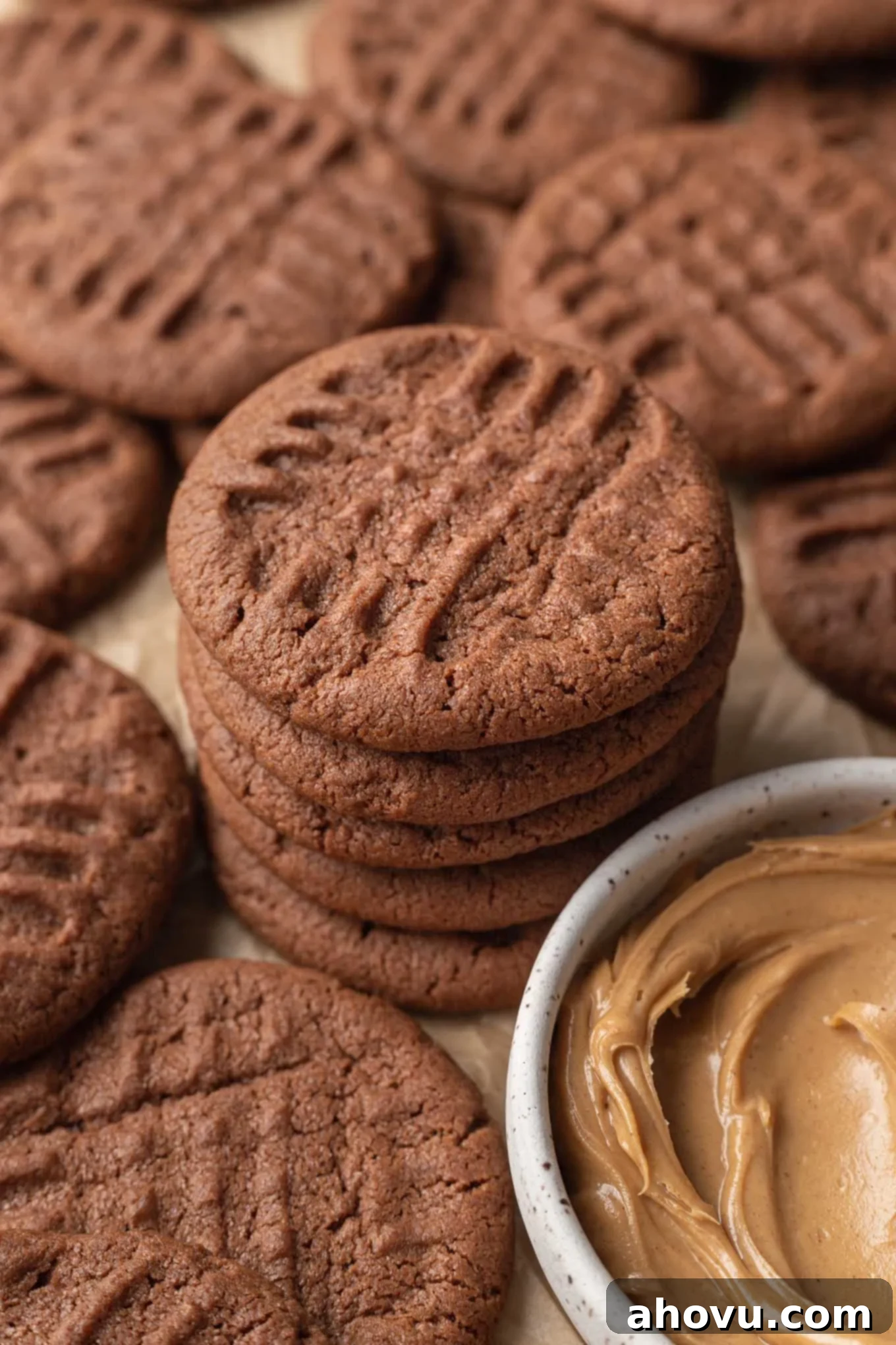A stack of chocolate peanut butter cookies next to a dish of peanut butter. 