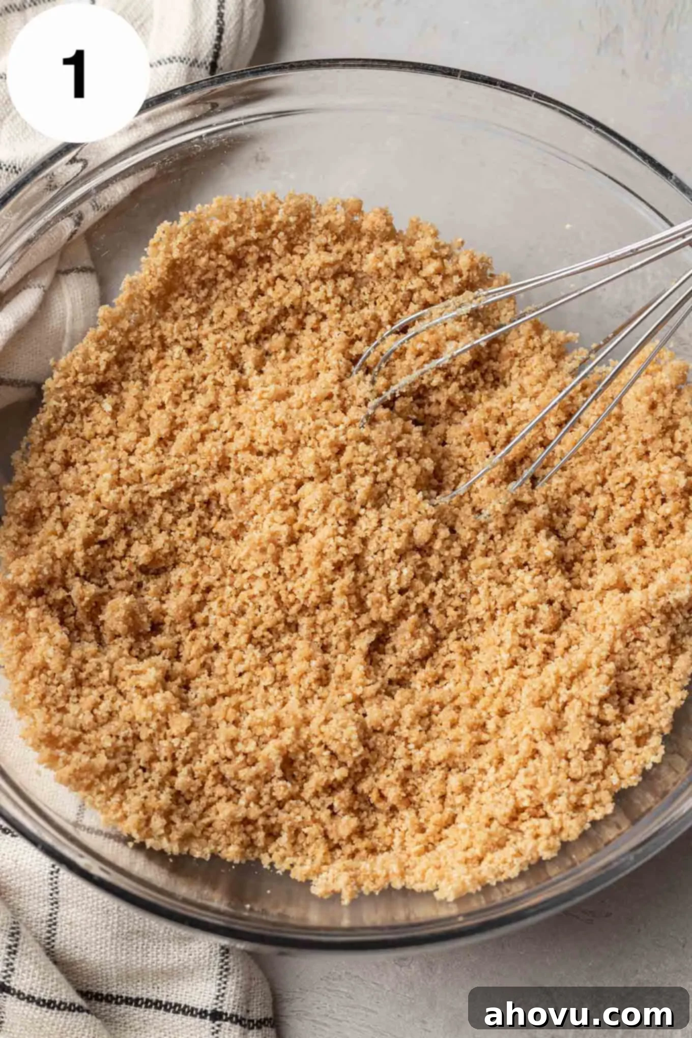 The graham cracker crust mixture mixed together in a glass mixing bowl.