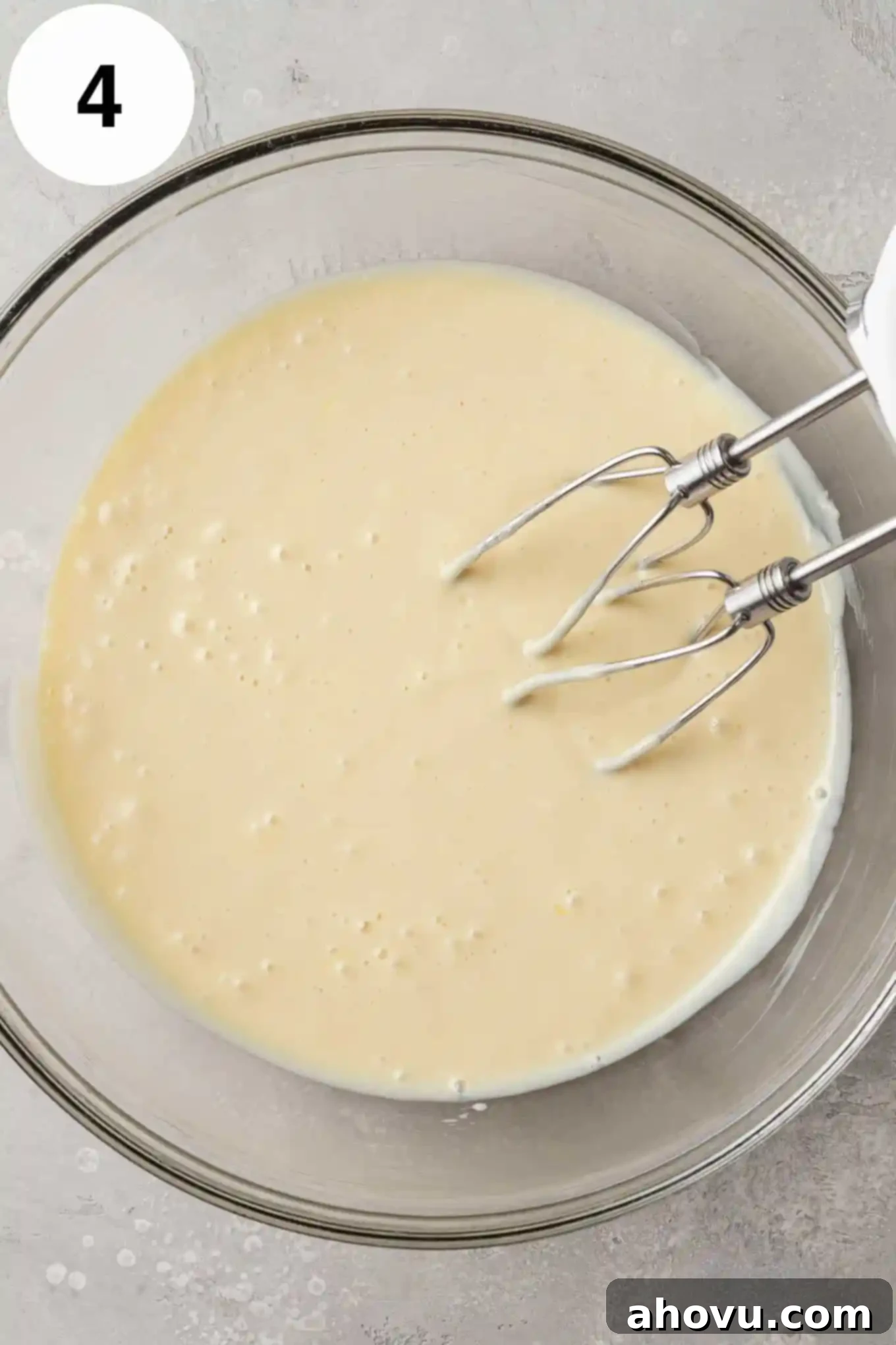 An overhead view of key lime pie filling in a glass mixing bowl. 
