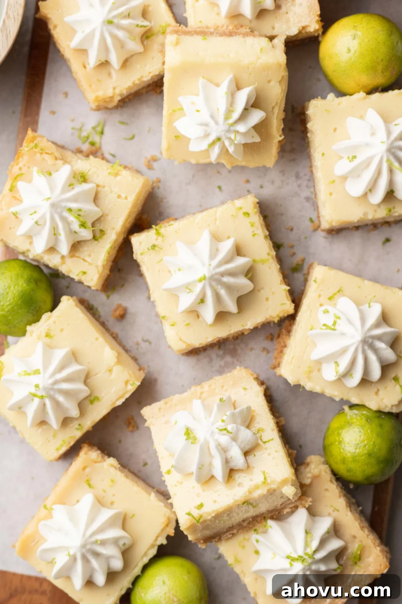 An overhead view of sliced key lime pie bars topped with whipped cream. 