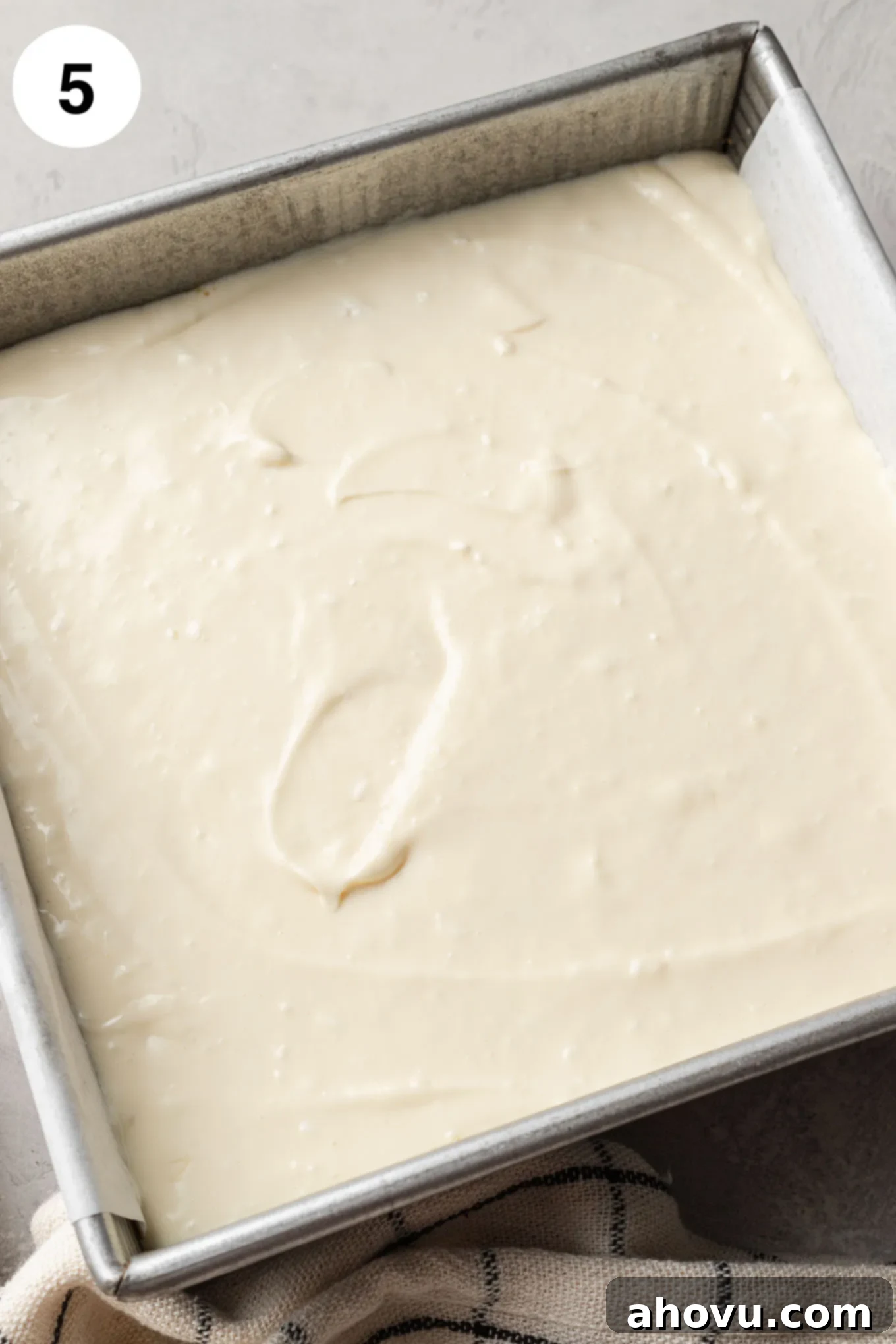 Creamy Cheesecake Squares 8 An overhead view of unbaked cheesecake bars in a square baking dish.