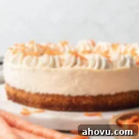 A carrot cake cheesecake topped with whipped cream on a marble serving platter.