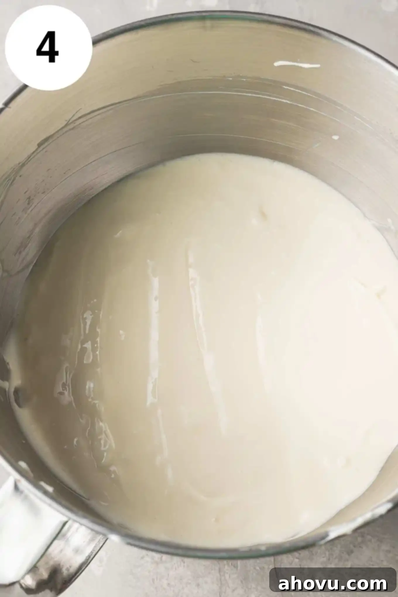 An overhead view of the creamy cheesecake filling in the bowl of a stand mixer, ready for assembly.