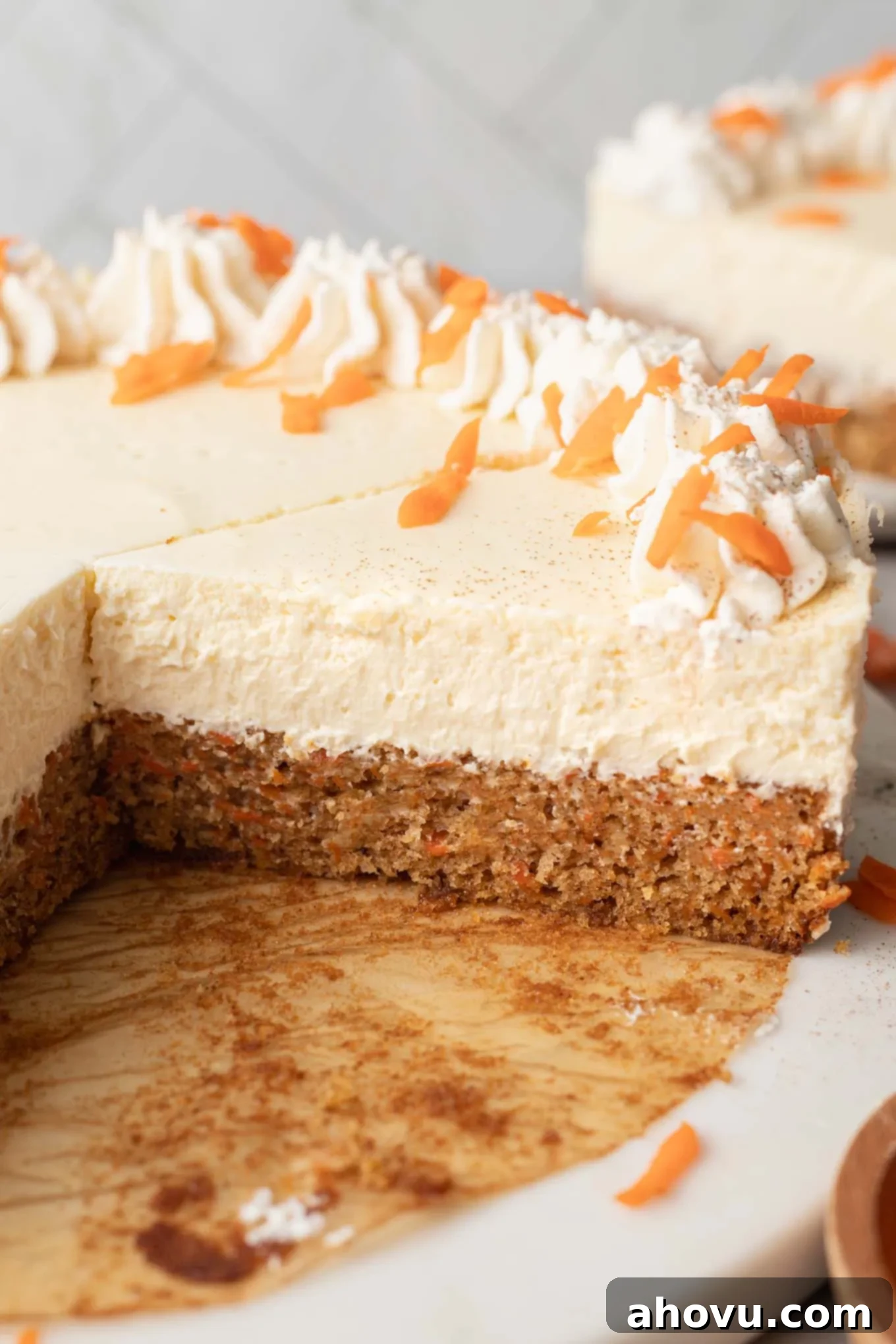 A side view of a perfectly sliced carrot cake cheesecake, showing the distinct layers of cake and cheesecake.