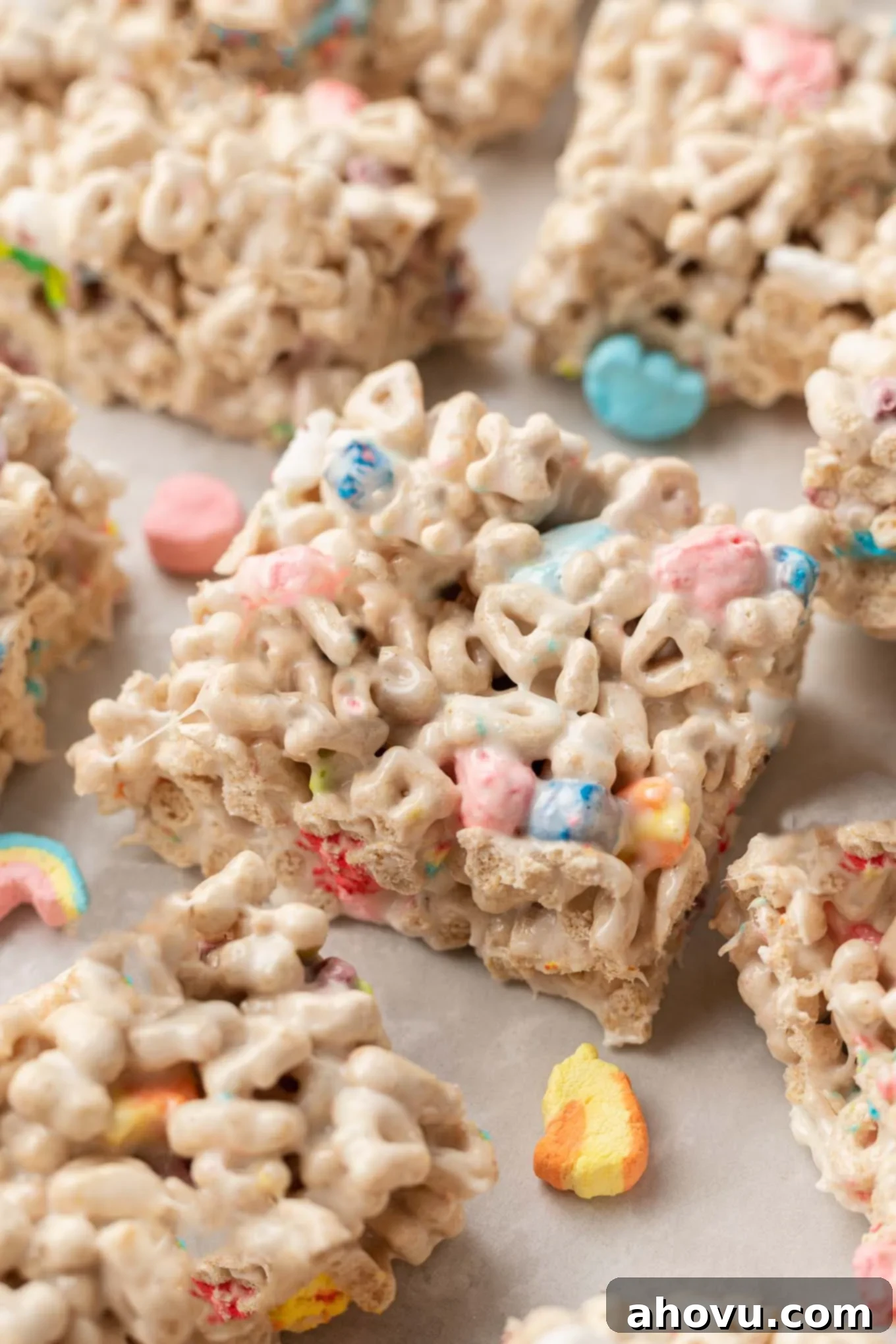 Lucky Charms Treats 2 A close-up view of perfectly sliced Lucky Charms bars on parchment paper, showcasing their vibrant colors and chewy texture.