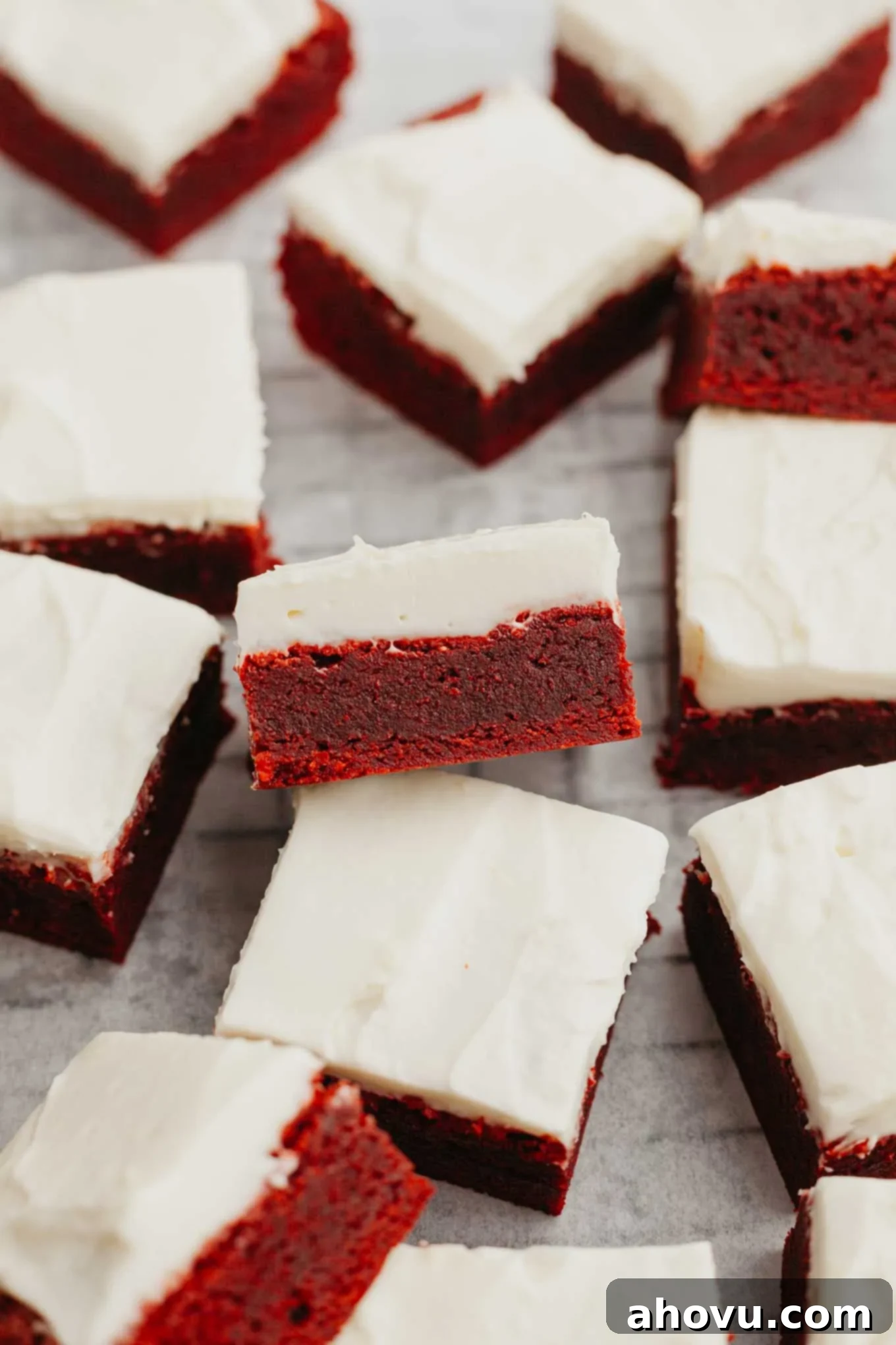 Frosted red velvet brownies sliced and arranged on a wire rack. 
