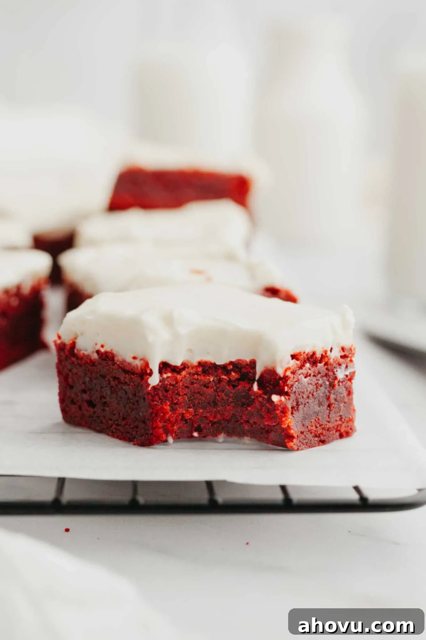 A side view of a red velvet brownie with a bite missing. 