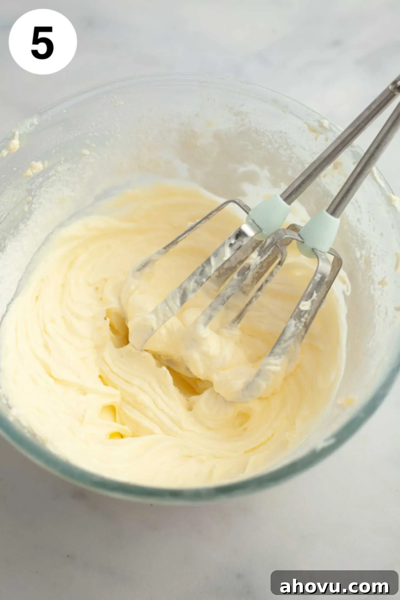 Cream cheese icing mixed together in a glass mixing bowl.