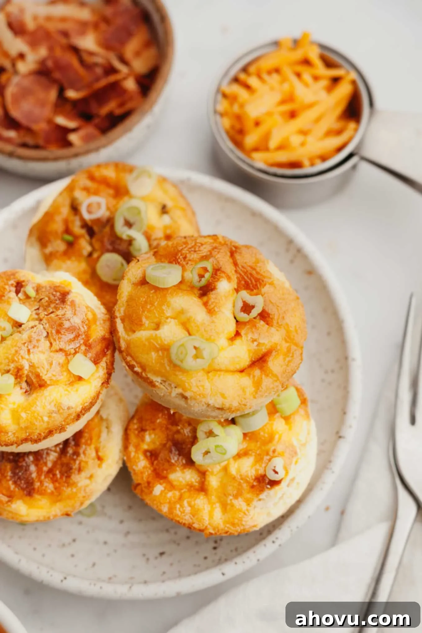 A stack of mini quiches on a speckled white plate, showing their golden crusts and savory filling.