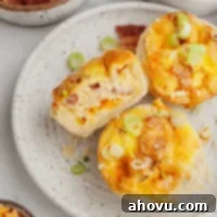 An overhead view of three mini quiches on a speckled white plate. One quiche is laying on it's side with a bite missing, invitingly showcasing its texture.