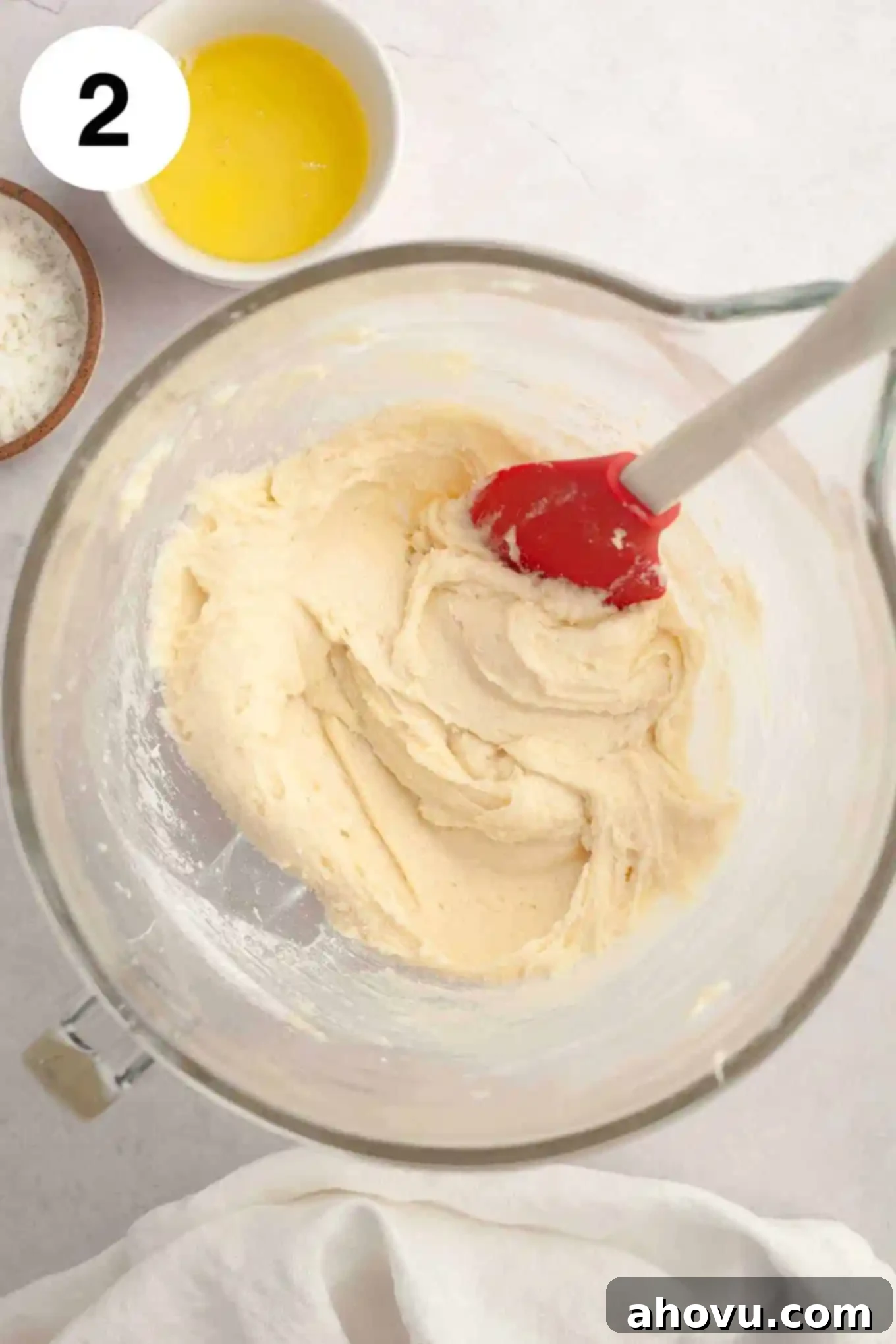 An overhead shot of the creamy, light coconut cupcake batter in a glass mixing bowl, perfectly smooth and ready for the next steps.