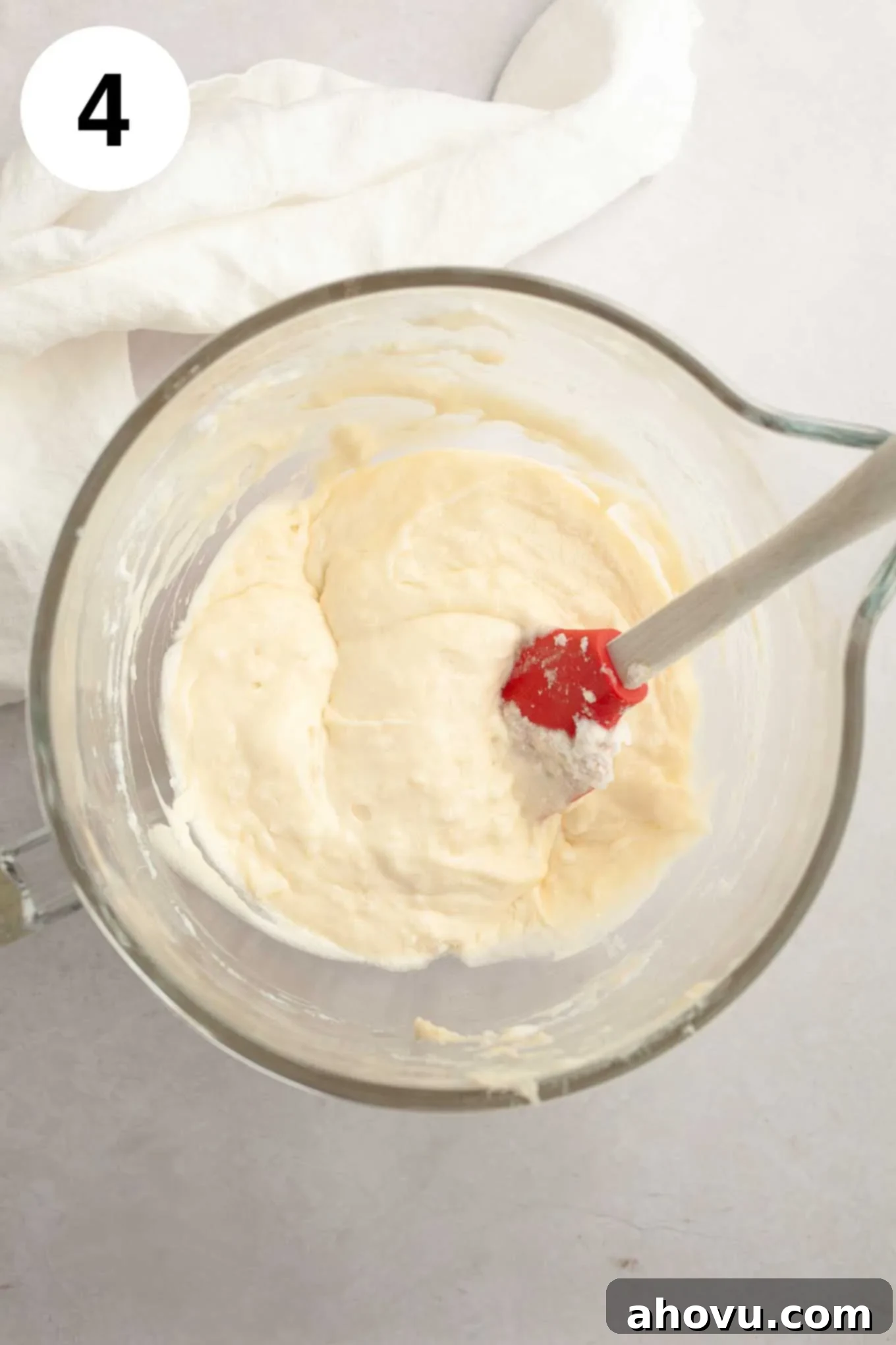 An overhead view of the completed coconut cupcake batter in a glass mixing bowl, smooth and ready for baking.