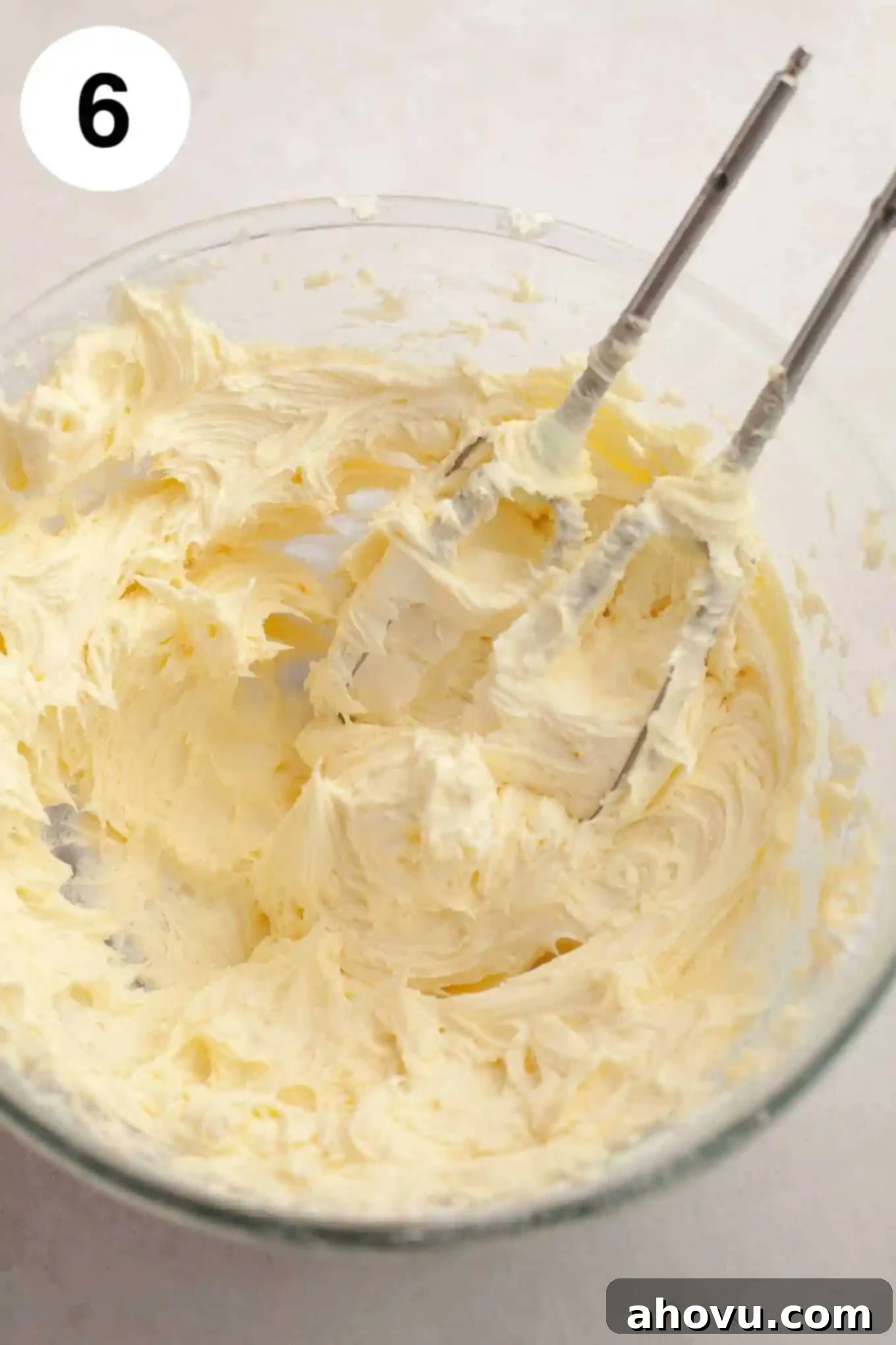 Creamy coconut frosting in a pristine glass mixing bowl, with the beaters of an electric mixer resting inside, ready for piping.