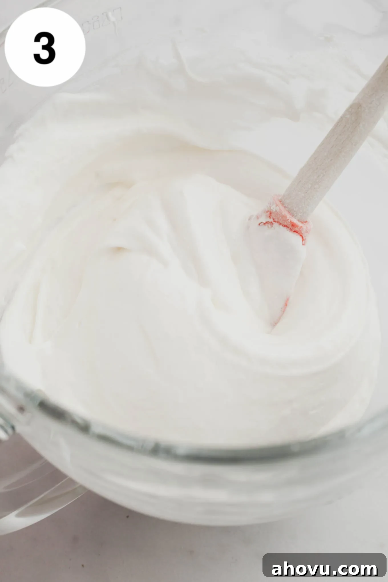 Smooth and airy angel food cupcake batter ready for baking, shown in a large glass mixing bowl.