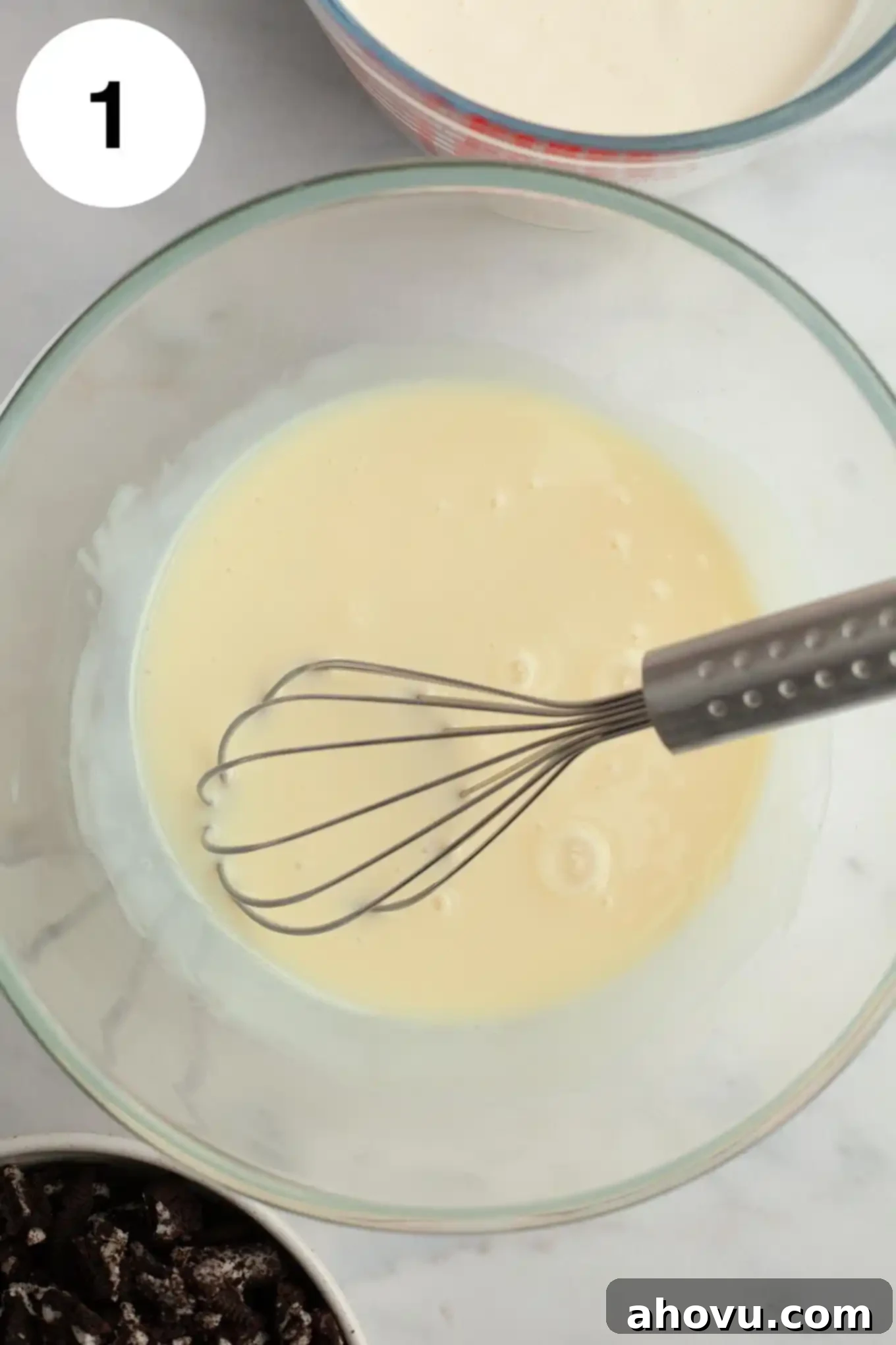 Midnight Cookie Dream 4 An overhead view of sweetened condensed milk in a glass mixing bowl with a whisk.