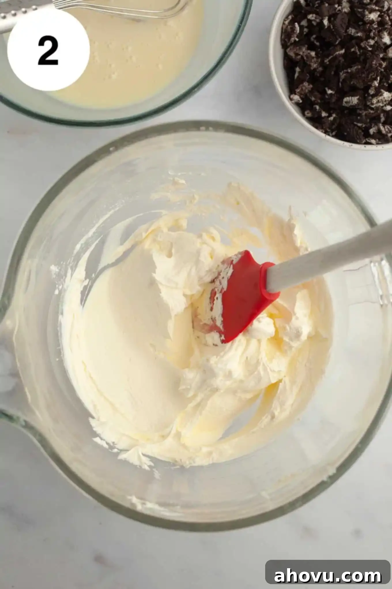 Midnight Cookie Dream 5 An overhead view of whipped cream in a glass mixing bowl with a rubber spatula.