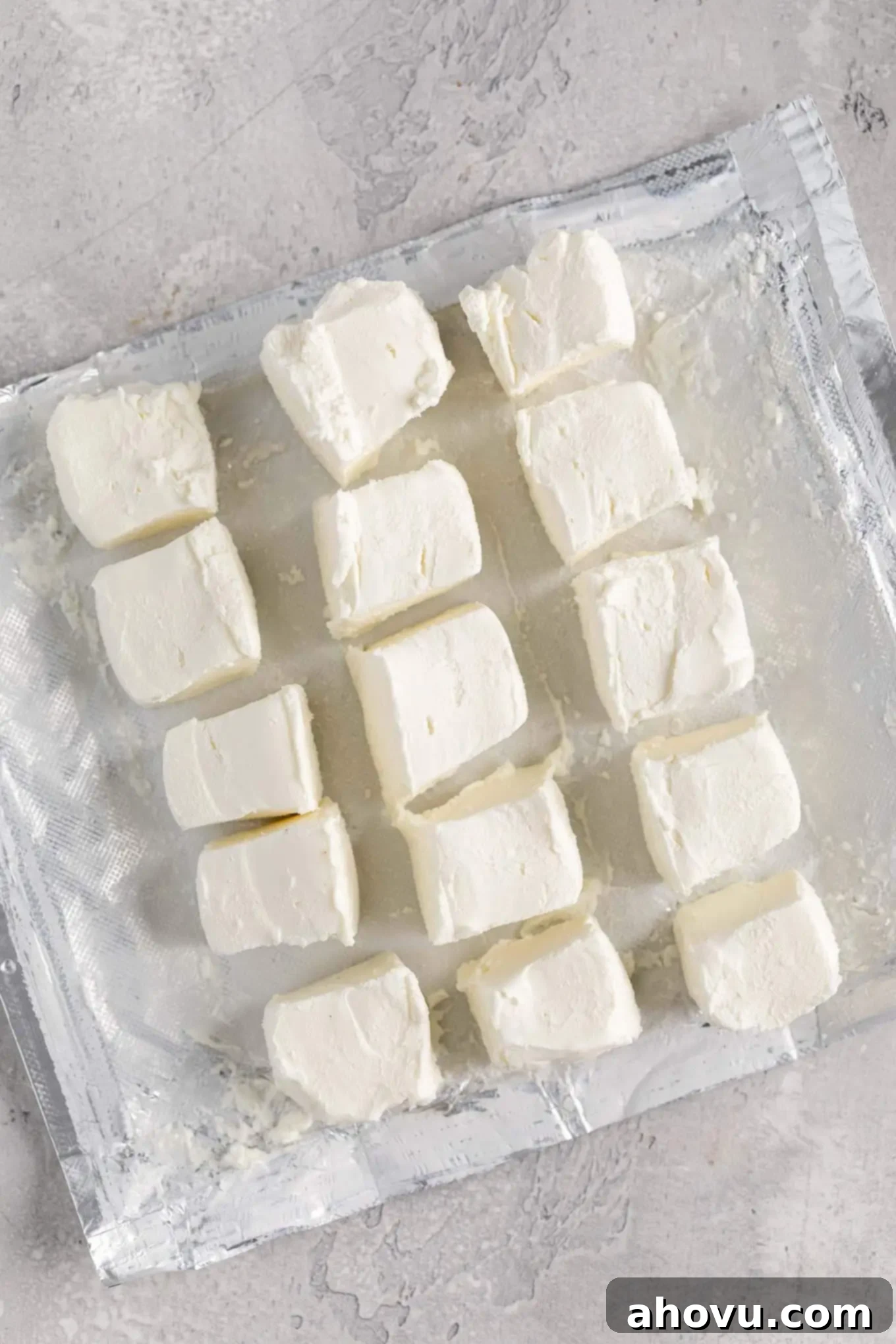 An overhead view of an opened package of cream cheese that's been neatly cubed into several small pieces, ready for quicker softening at room temperature.