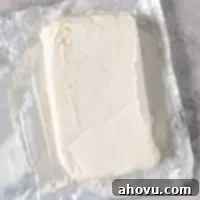 A block of cream cheese that's been opened and is sitting on the wrapper, ready for use after softening.