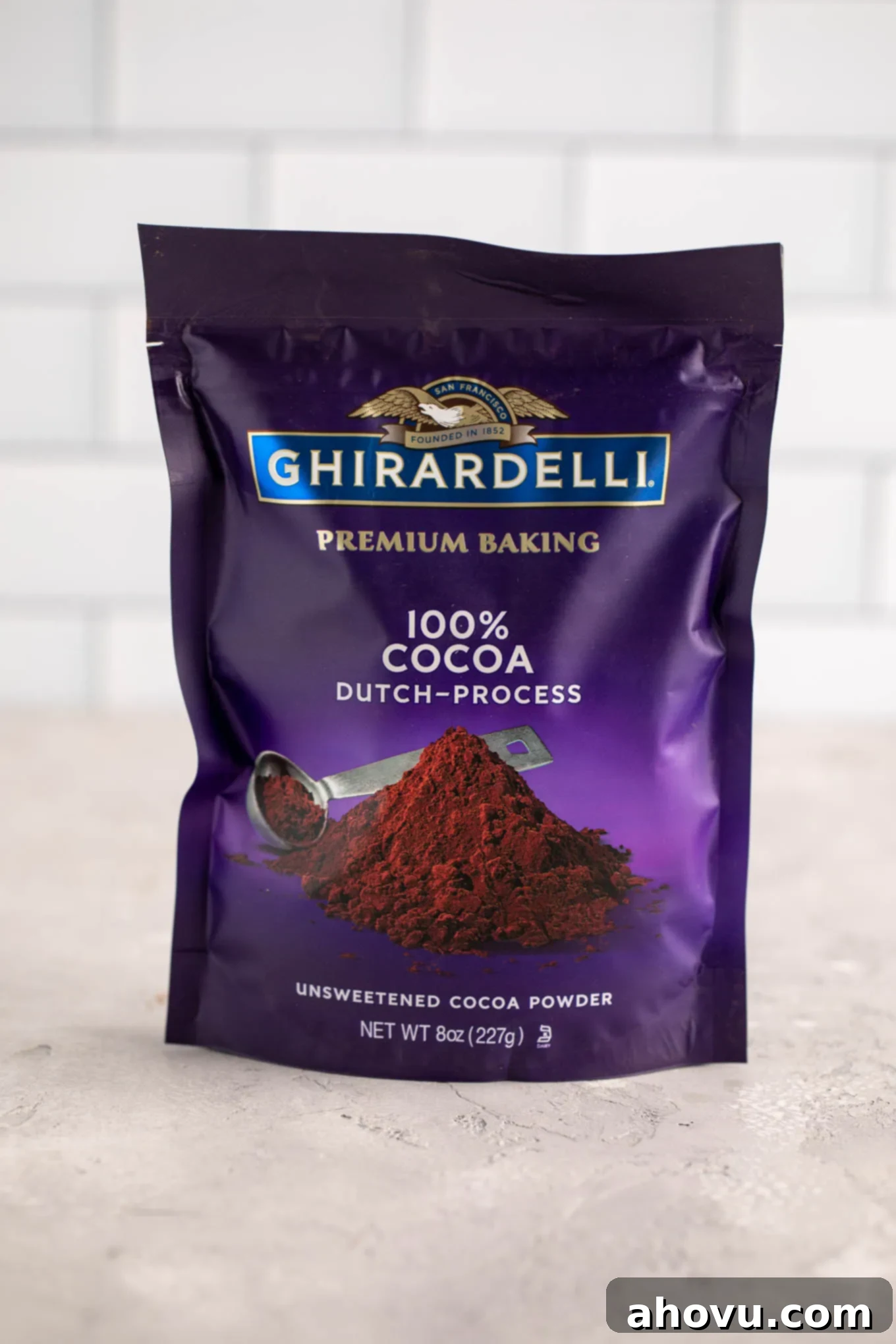 A package of Ghirardelli Dutch process cocoa powder on a gray surface.