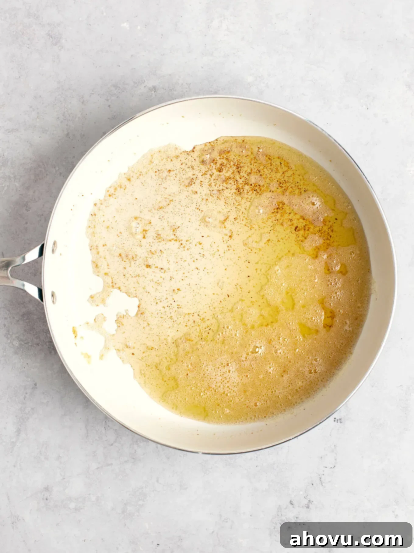 The Art of Brown Butter 6 Foamy butter in a white skillet with early signs of browning milk solids at the bottom.